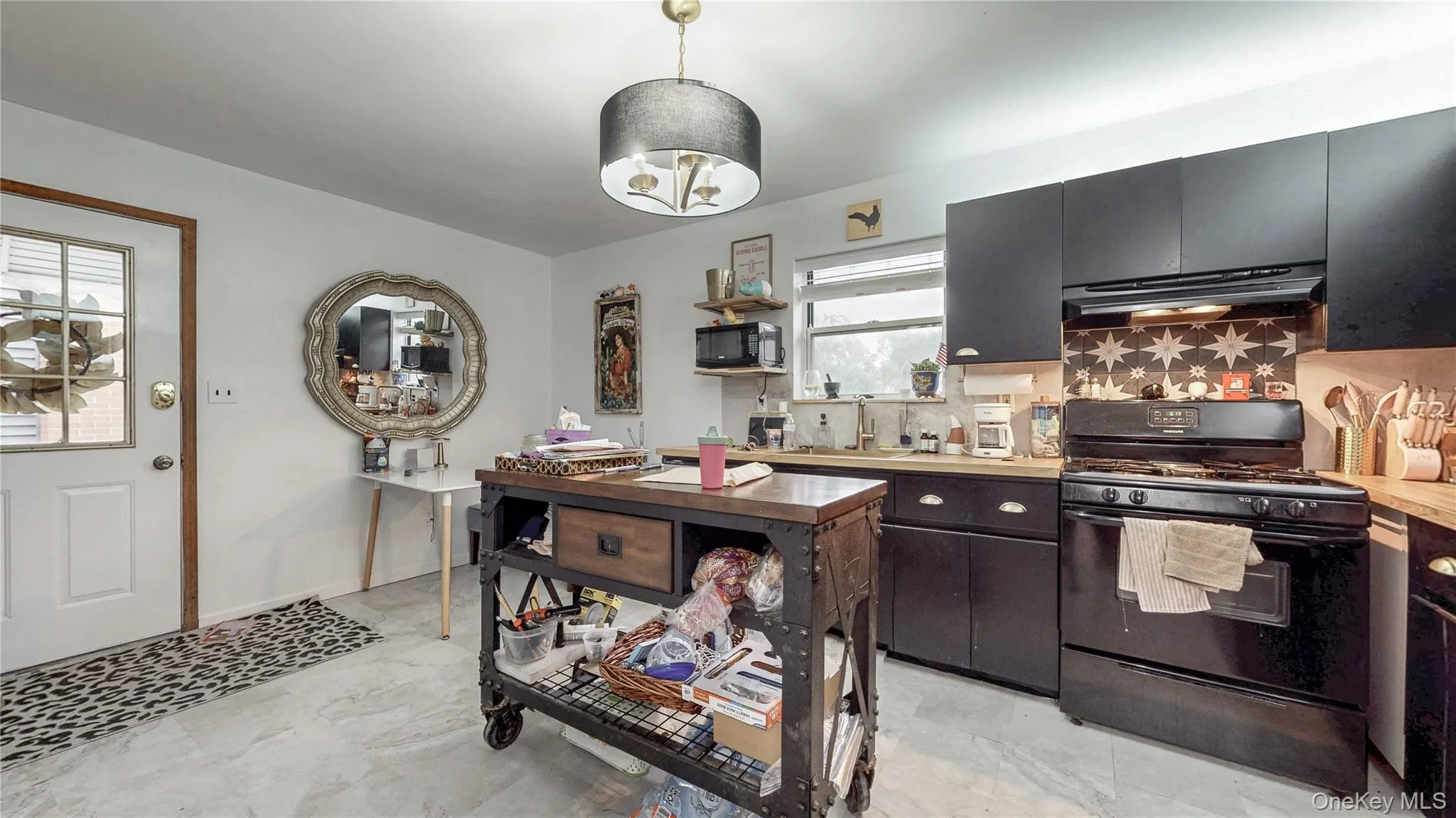 Kitchen featuring black appliances, light countertops, decorative backsplash, exhaust hood, and dark cabinets Kitchen featuring black appliances, light countertops, decorative backsplash, exhaust hood, and dark cabinets