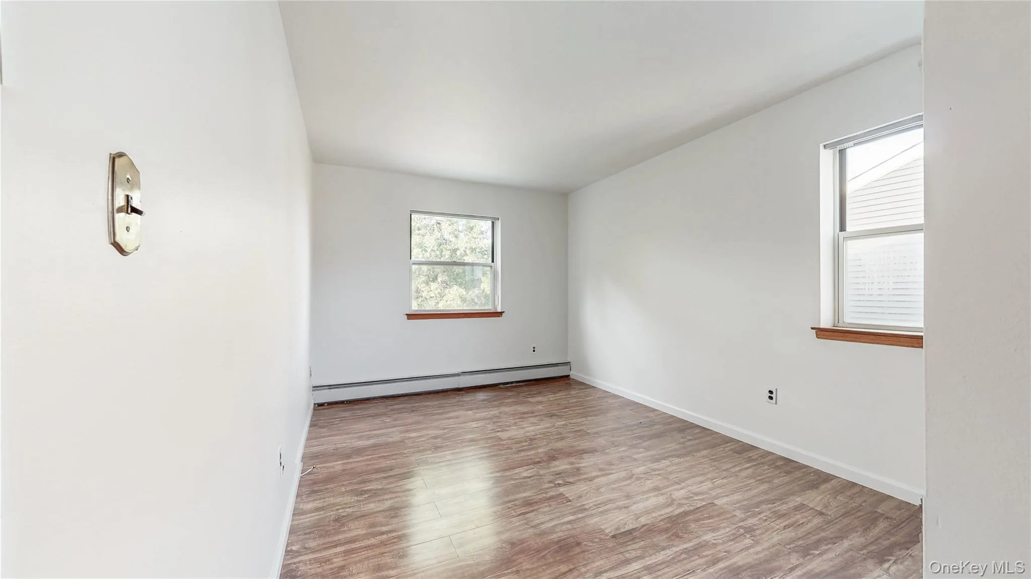 Unfurnished room with light wood-style flooring and a baseboard heating unit Unfurnished room with light wood-style flooring and a baseboard heating unit