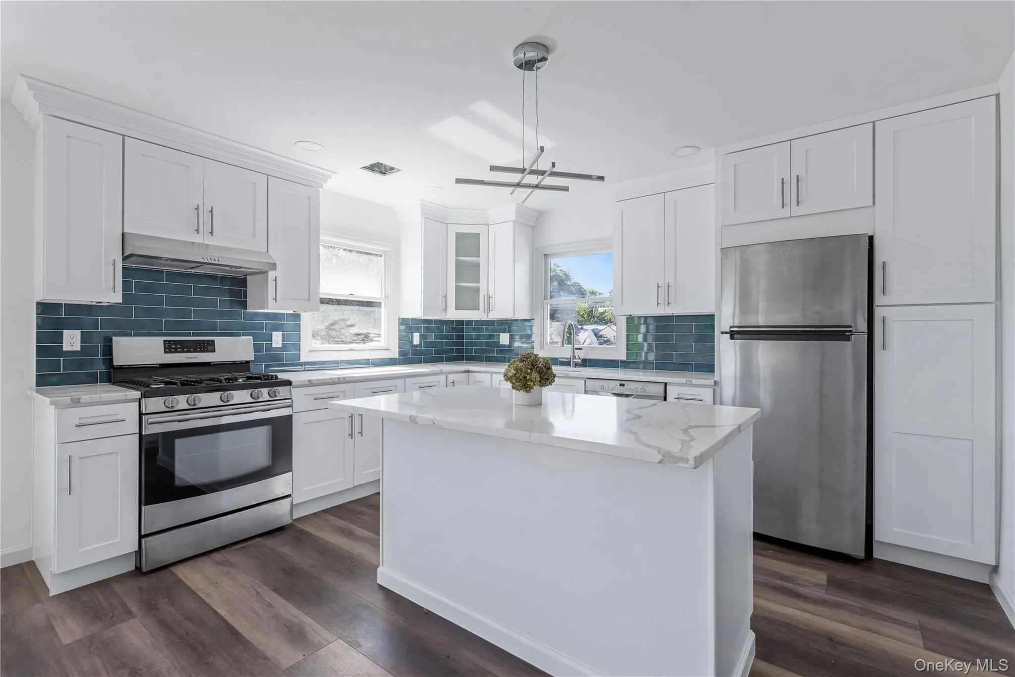 Kitchen with stainless steel appliances, decorative backsplash, white cabinets, a center island, and light stone countertops Kitchen with stainless steel appliances, decorative backsplash, white cabinets, a center island, and light stone countertops
