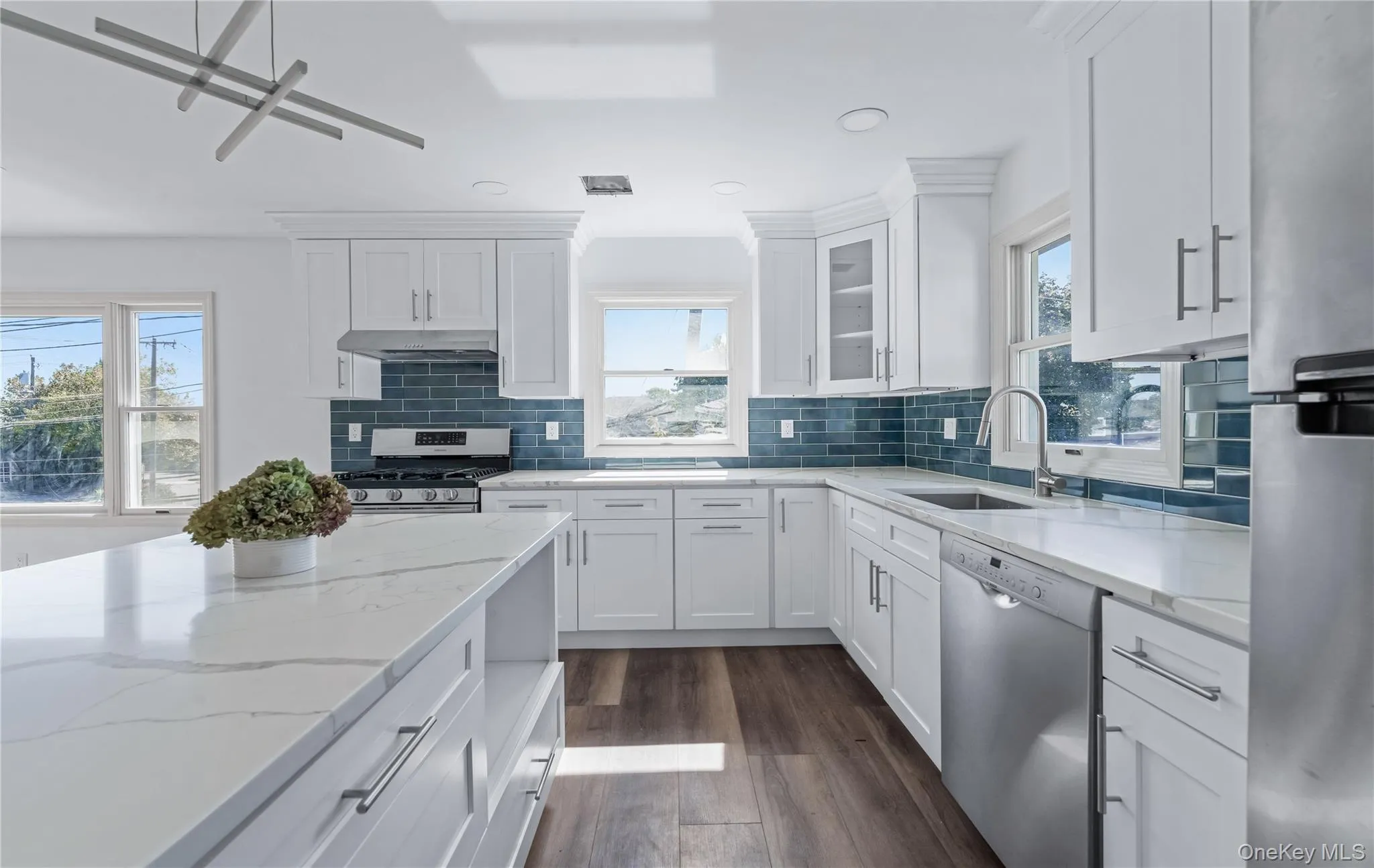 Kitchen with decorative backsplash, white cabinetry, dark wood-type flooring, and recessed lighting Kitchen with decorative backsplash, white cabinetry, dark wood-type flooring, and recessed lighting