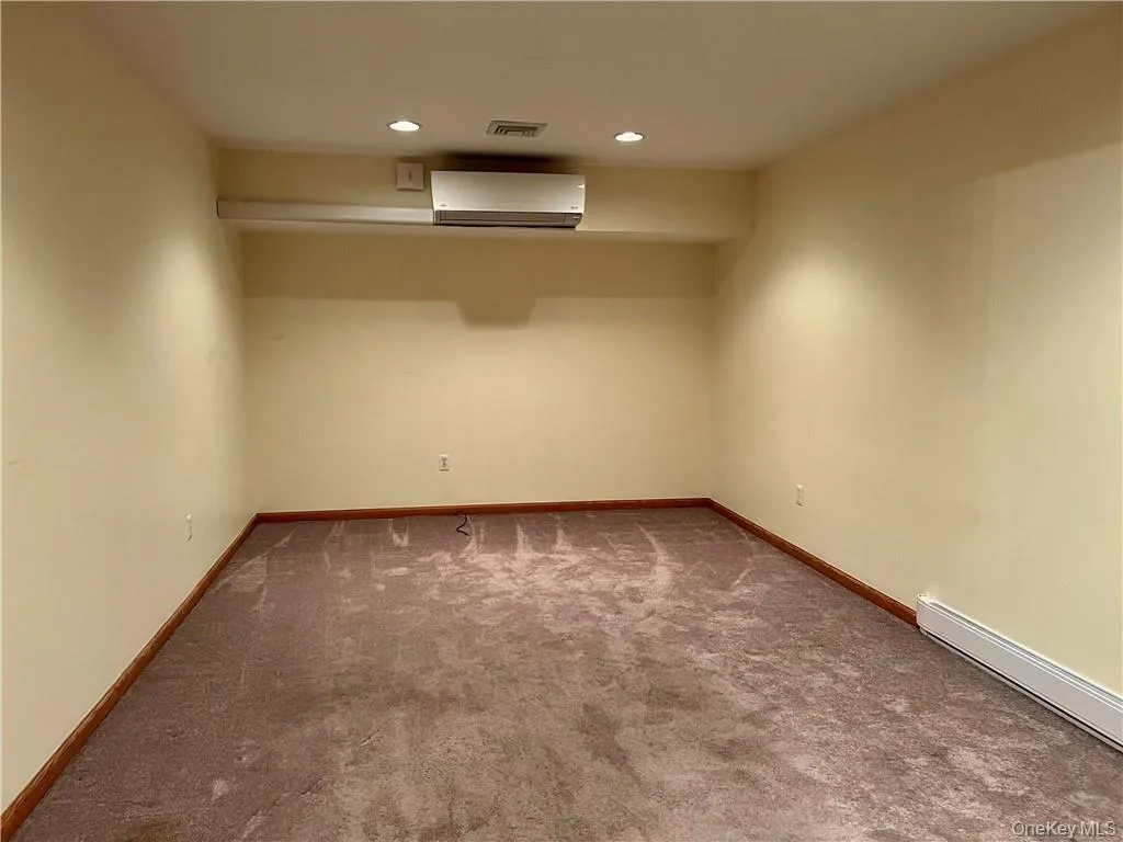 Empty room with carpet, recessed lighting, a wall unit AC, and a baseboard heating unit Empty room with carpet, recessed lighting, a wall unit AC, and a baseboard heating unit