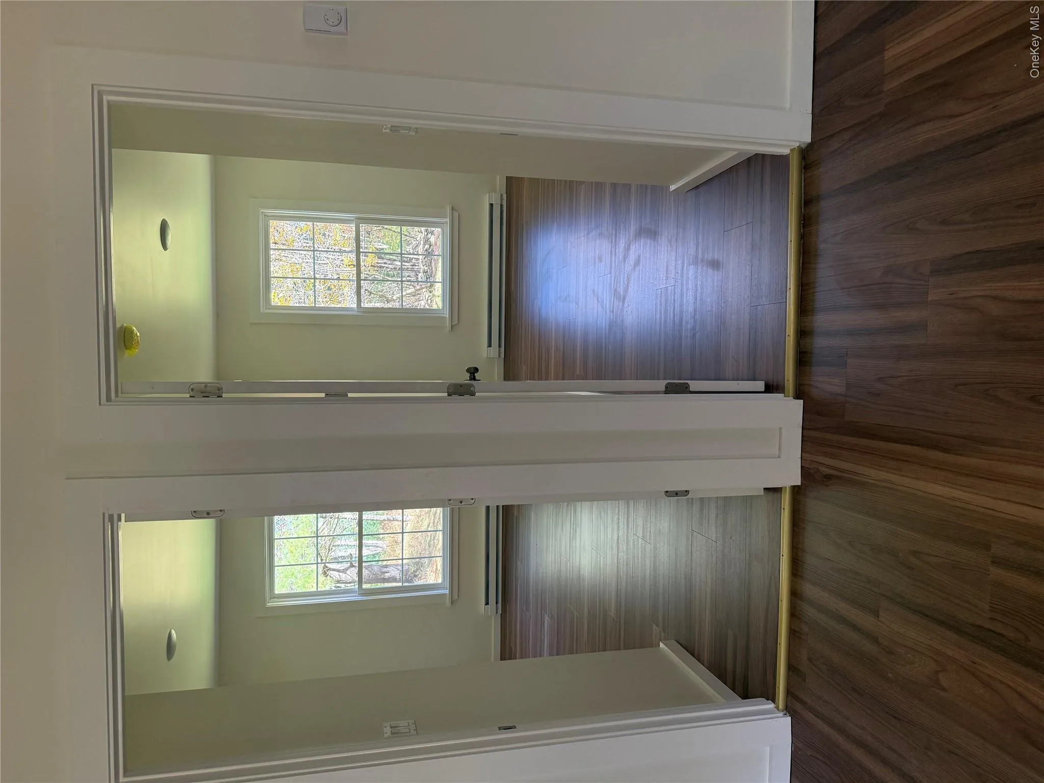 Hall featuring dark wood-style floors, healthy amount of natural light, and a baseboard radiator Hall featuring dark wood-style floors, healthy amount of natural light, and a baseboard radiator
