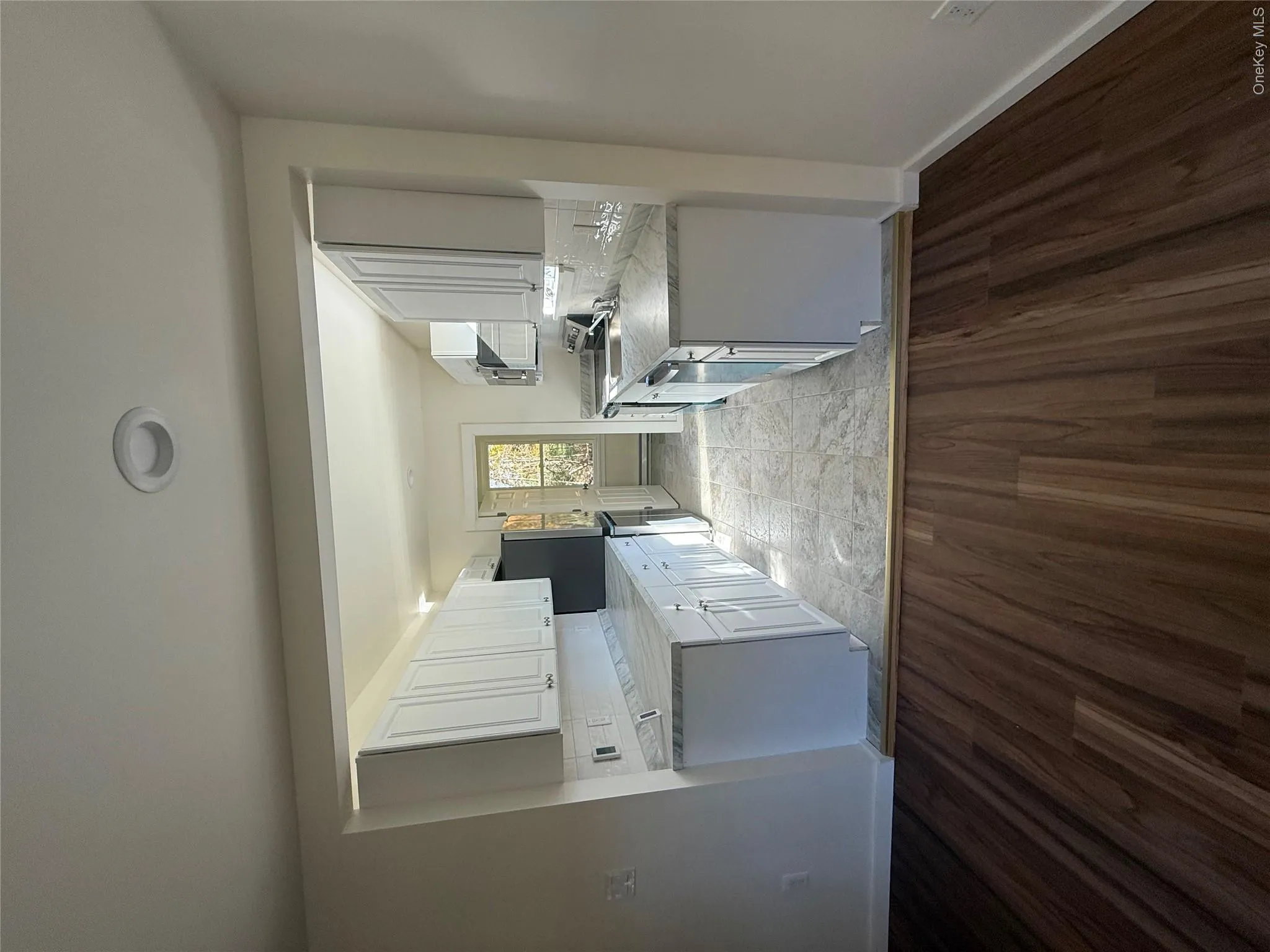 Kitchen with decorative backsplash, light countertops, light wood-type flooring, and white cabinets Kitchen with decorative backsplash, light countertops, light wood-type flooring, and white cabinets