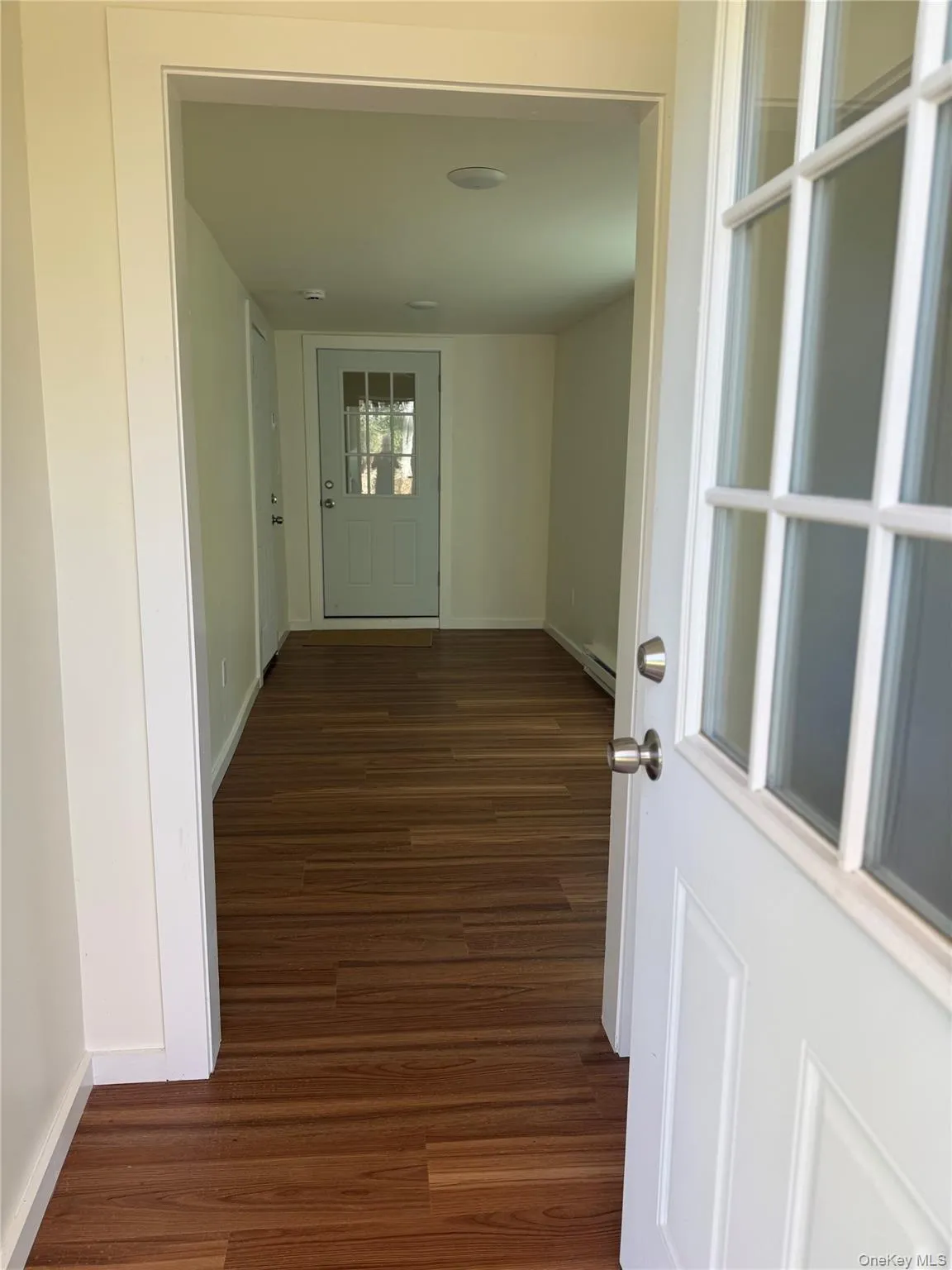 Corridor with dark wood-style flooring and baseboards Corridor with dark wood-style flooring and baseboards