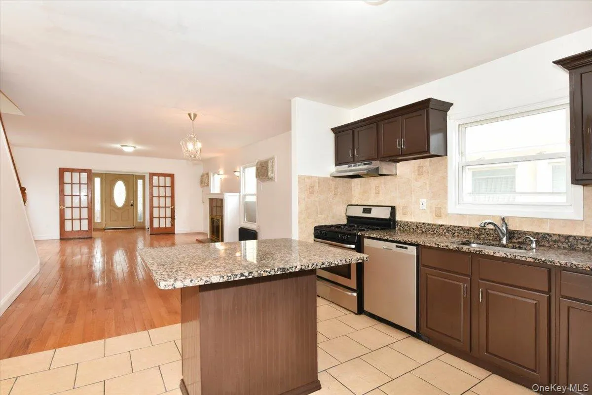 Kitchen with plenty of natural light, stainless steel appliances, dark stone counters, and light tile patterned flooring Kitchen with plenty of natural light, stainless steel appliances, dark stone counters, and light tile patterned flooring