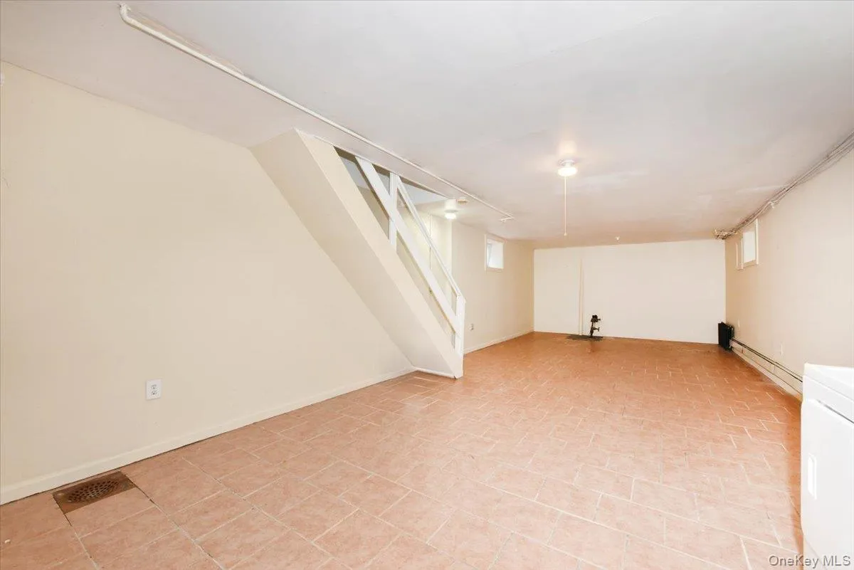Below grade area featuring a baseboard heating unit, stairs, and washer / clothes dryer Below grade area featuring a baseboard heating unit, stairs, and washer / clothes dryer
