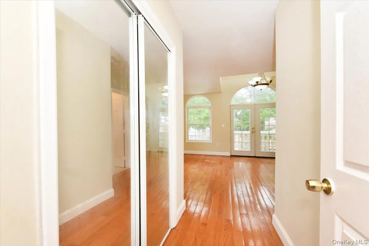 Corridor with light wood-style flooring, a chandelier, and french doors Corridor with light wood-style flooring, a chandelier, and french doors