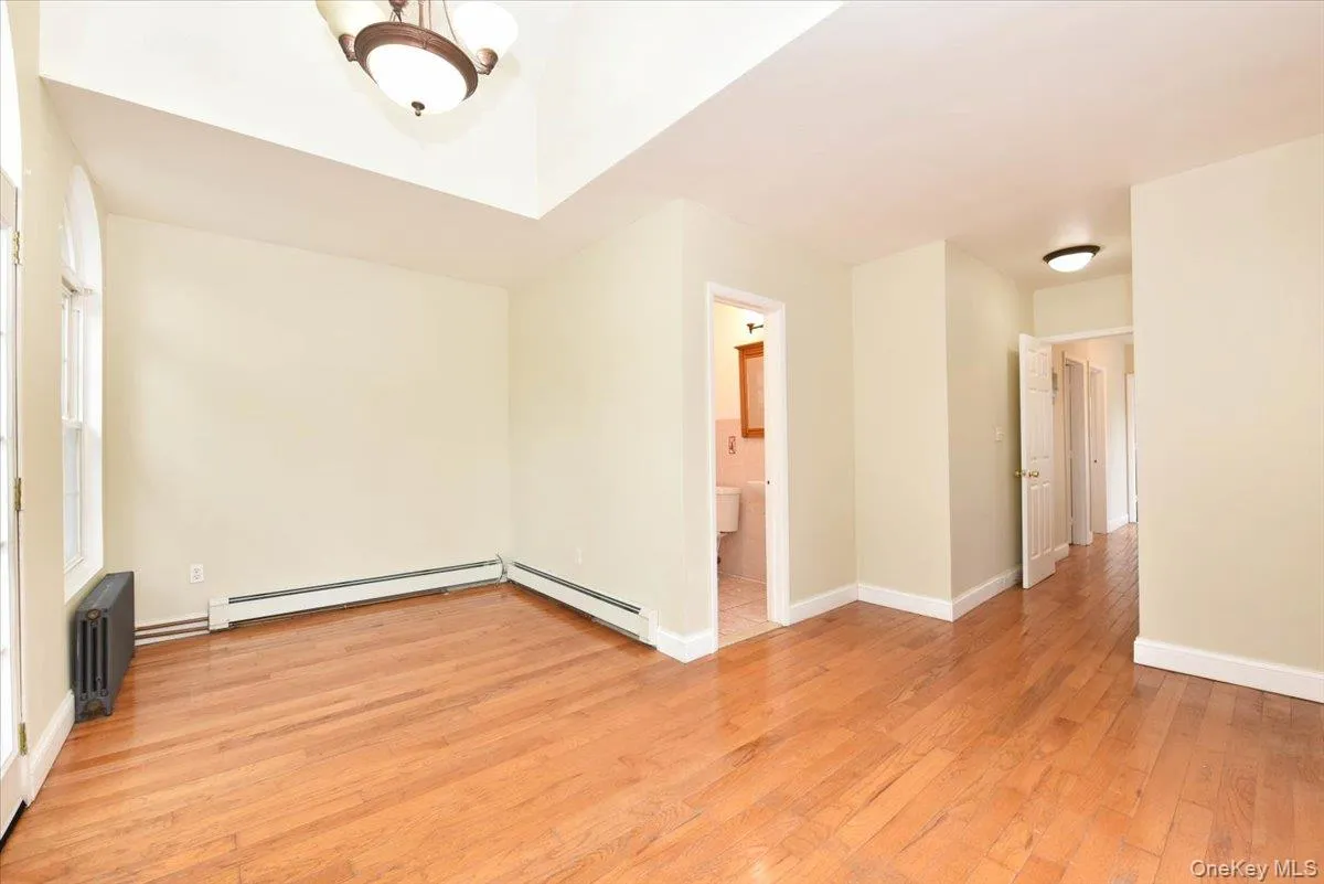 Unfurnished room featuring light wood finished floors, radiator, and a baseboard heating unit Unfurnished room featuring light wood finished floors, radiator, and a baseboard heating unit