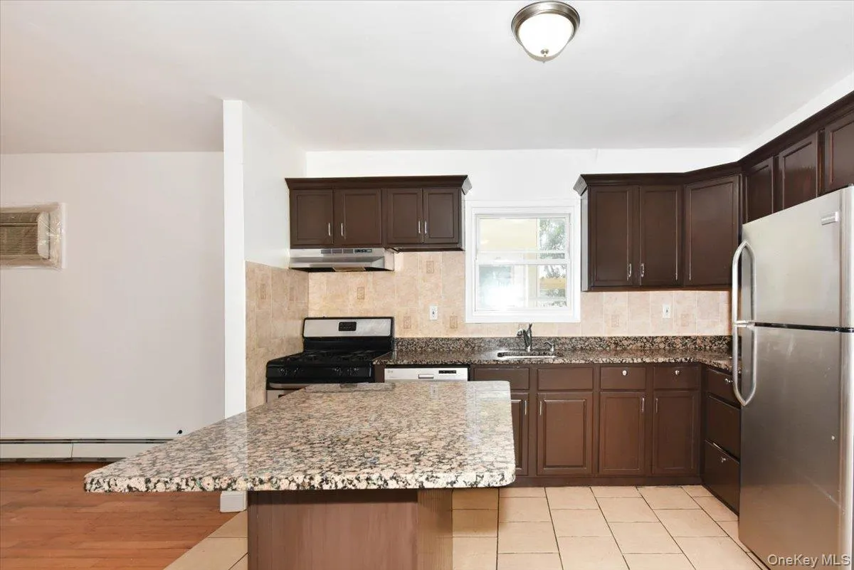Kitchen with stainless steel appliances, tasteful backsplash, dark stone countertops, and a center island Kitchen with stainless steel appliances, tasteful backsplash, dark stone countertops, and a center island