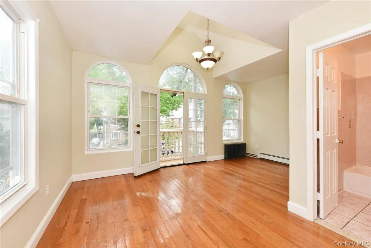 Doorway to outside featuring a chandelier, wood-type flooring, a baseboard radiator, and radiator heating unit Doorway to outside featuring a chandelier, wood-type flooring, a baseboard radiator, and radiator heating unit