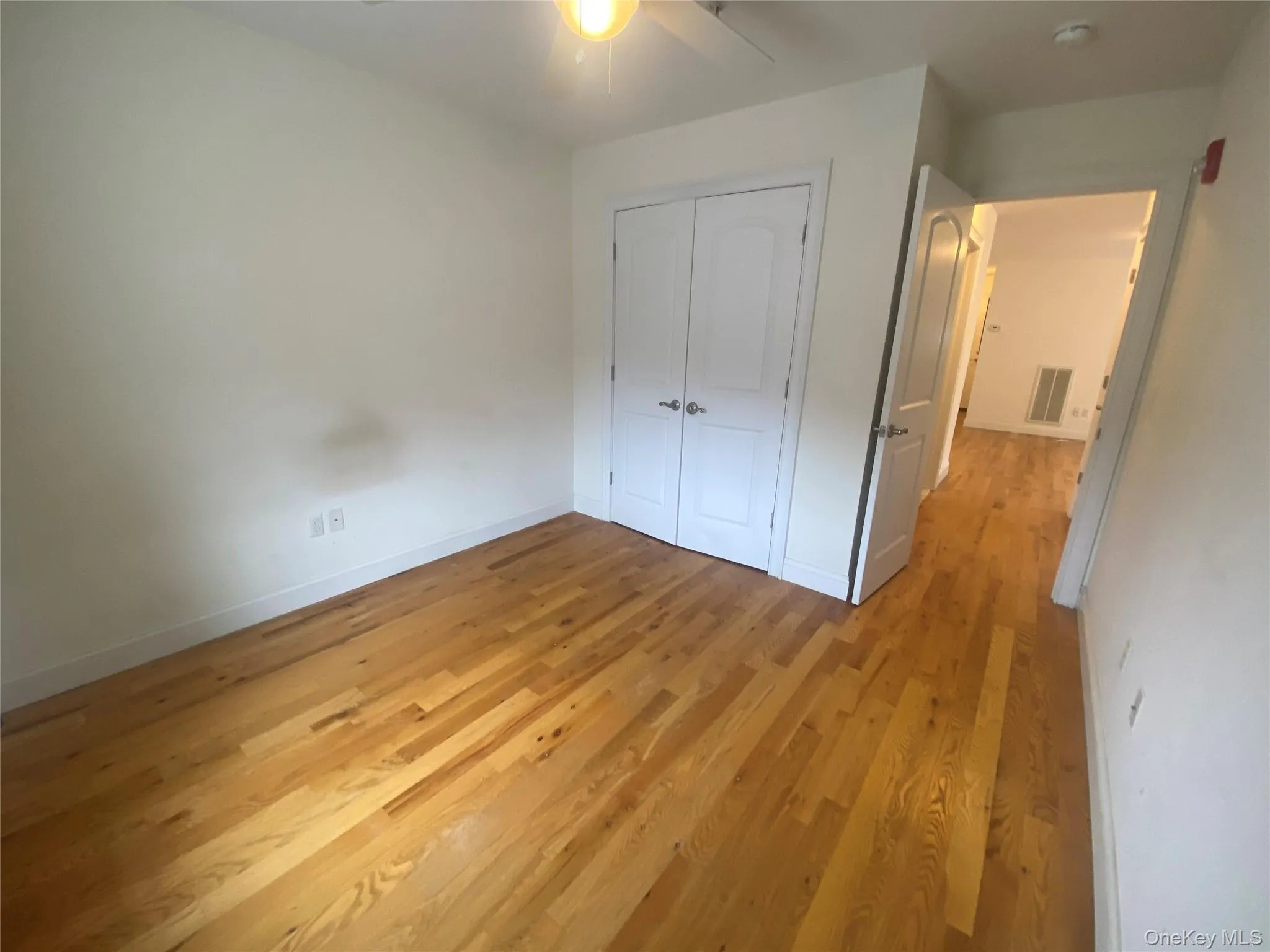 Unfurnished bedroom with light wood finished floors, a closet, and a ceiling fan Unfurnished bedroom with light wood finished floors, a closet, and a ceiling fan
