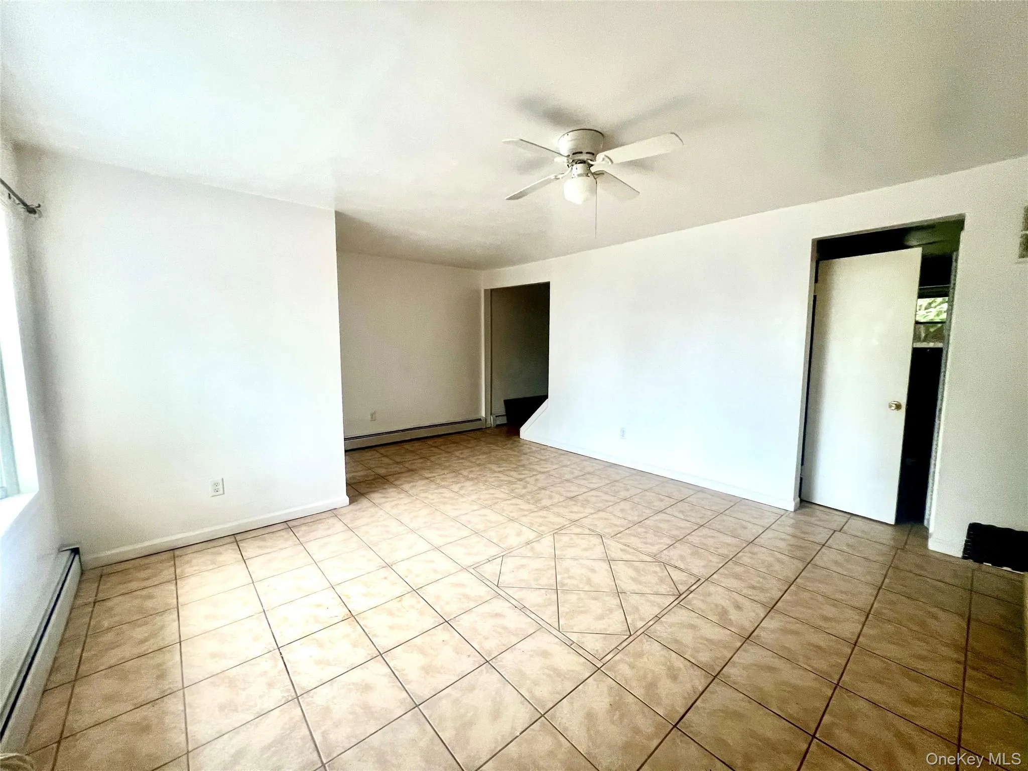 Spare room with baseboard heating, light tile patterned flooring, and ceiling fan Spare room with baseboard heating, light tile patterned flooring, and ceiling fan