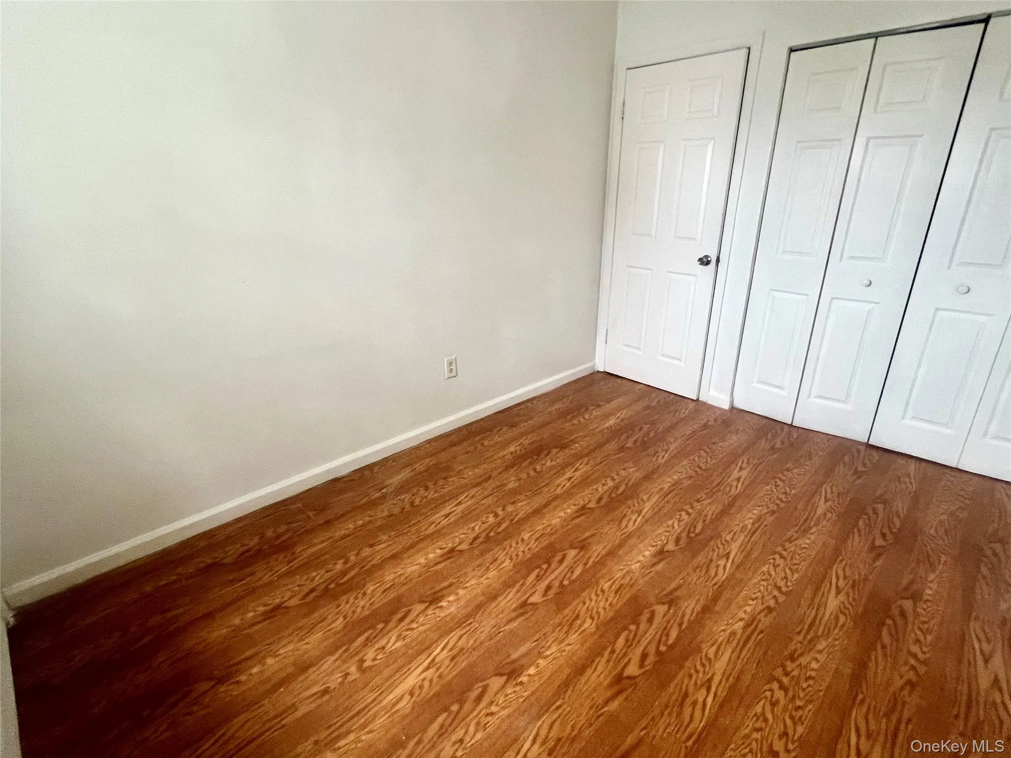 Unfurnished bedroom featuring dark wood-style flooring and a closet Unfurnished bedroom featuring dark wood-style flooring and a closet
