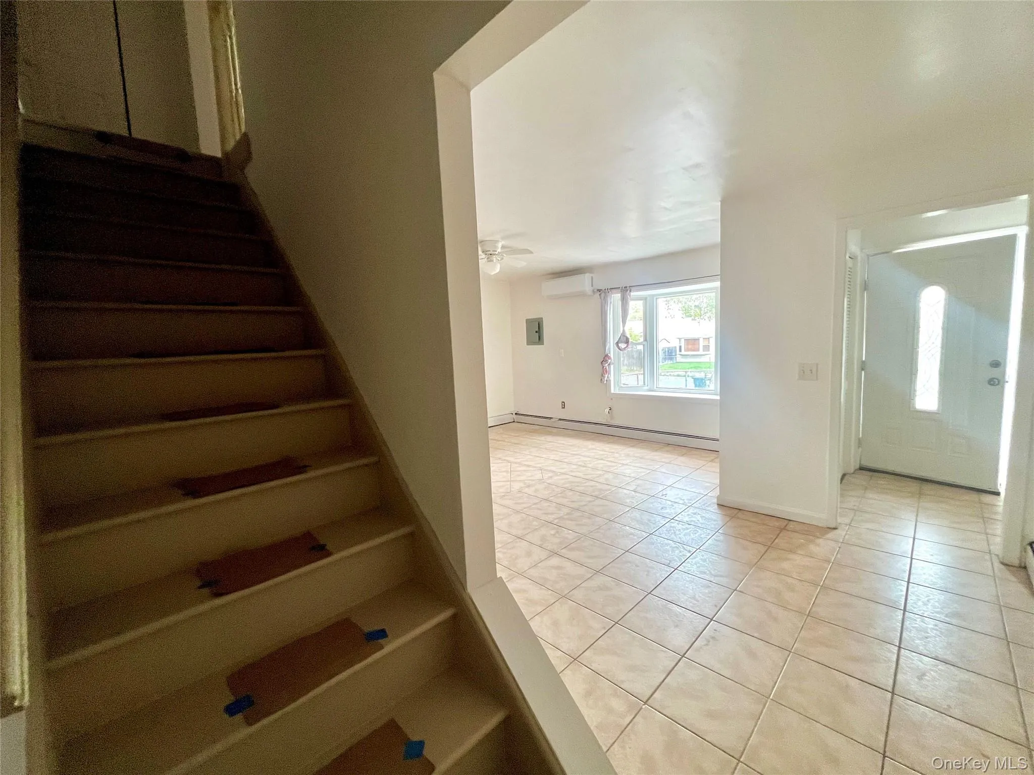 Stairs with tile patterned flooring, a baseboard radiator, and an AC wall unit Stairs with tile patterned flooring, a baseboard radiator, and an AC wall unit