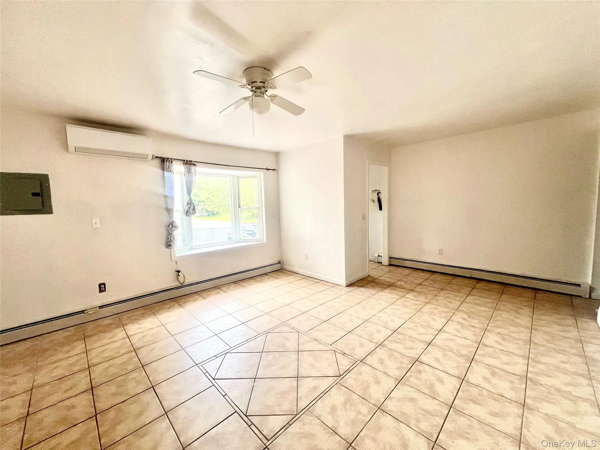 Empty room with a baseboard heating unit, light tile patterned floors, electric panel, and ceiling fan Empty room with a baseboard heating unit, light tile patterned floors, electric panel, and ceiling fan