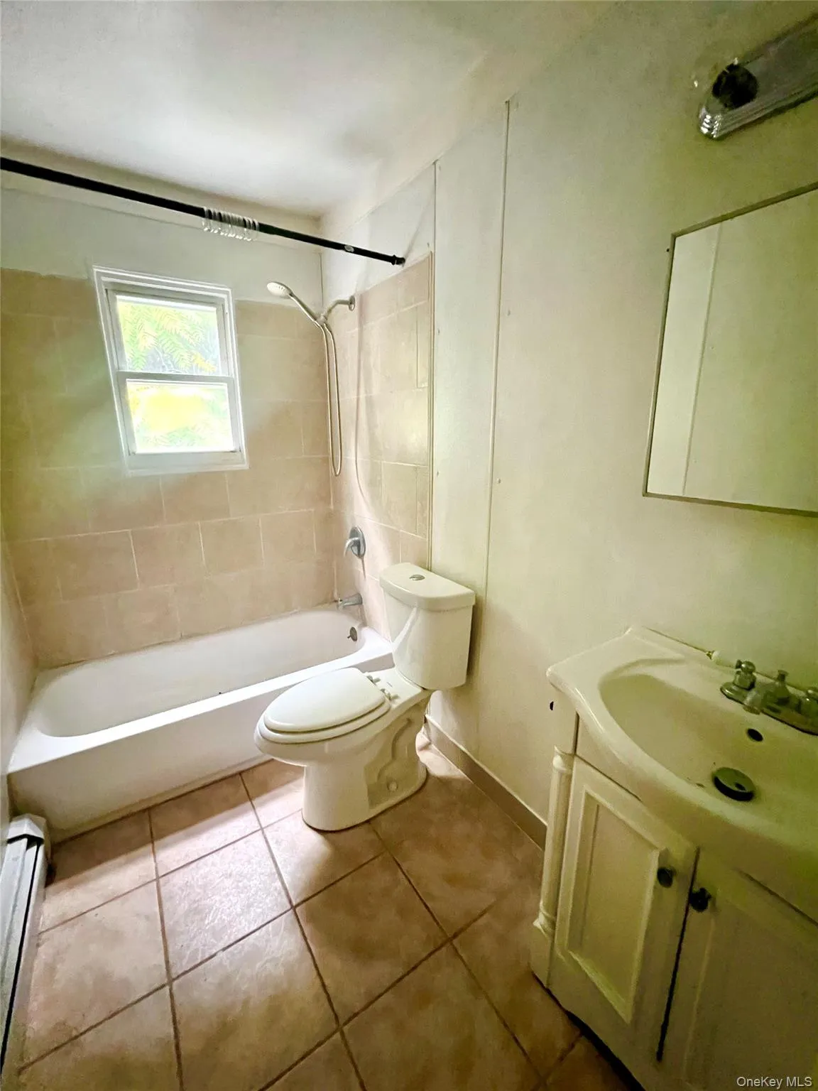 Full bathroom featuring bathtub / shower combination, vanity, light tile patterned floors, and a baseboard radiator Full bathroom featuring bathtub / shower combination, vanity, light tile patterned floors, and a baseboard radiator