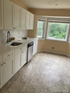 Kitchen featuring white cabinetry, light countertops, and dishwasher Kitchen featuring white cabinetry, light countertops, and dishwasher