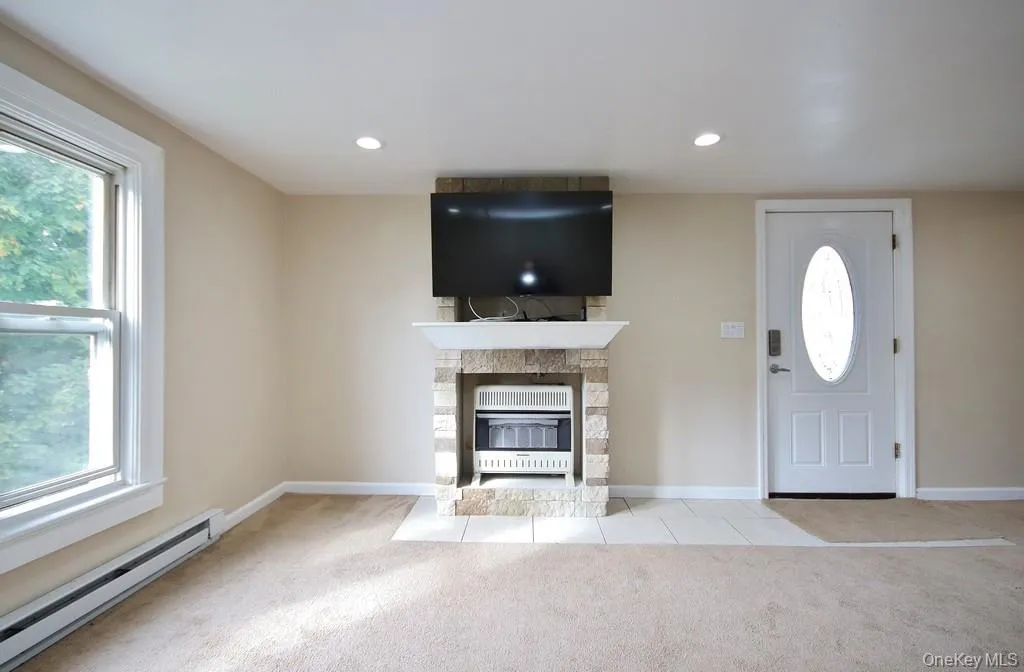 Unfurnished living room with a baseboard heating unit, plenty of natural light, carpet floors, and recessed lighting Unfurnished living room with a baseboard heating unit, plenty of natural light, carpet floors, and recessed lighting