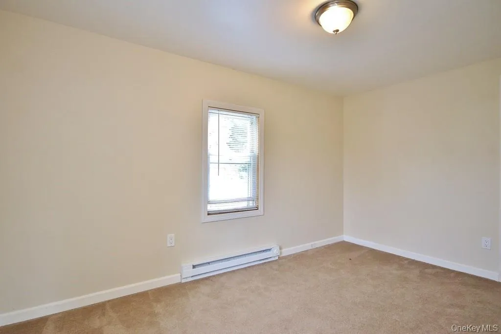 Spare room with a baseboard heating unit and carpet flooring Spare room with a baseboard heating unit and carpet flooring