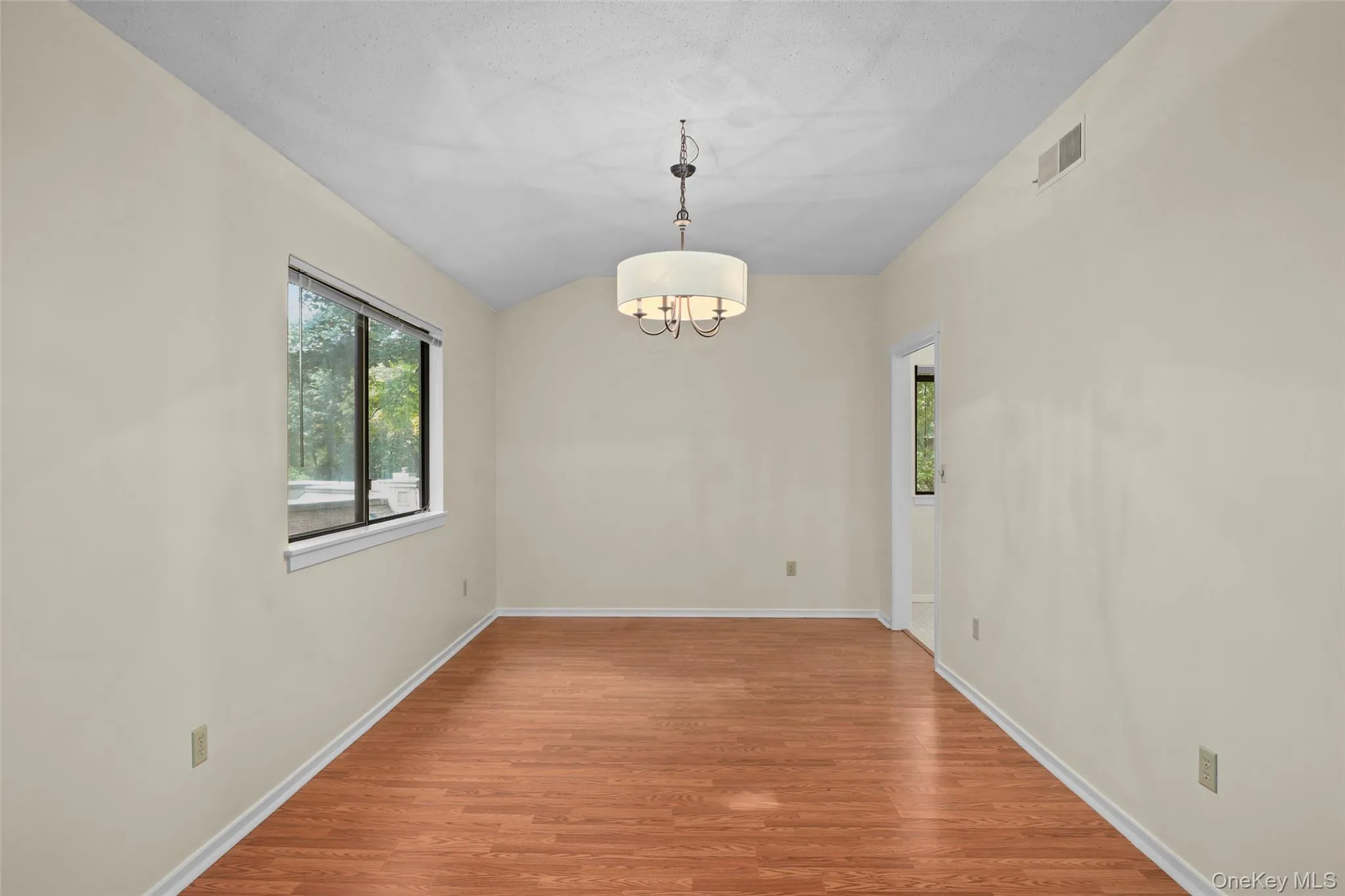 Unfurnished dining area with a chandelier, light wood-style flooring, and vaulted ceiling Unfurnished dining area with a chandelier, light wood-style flooring, and vaulted ceiling