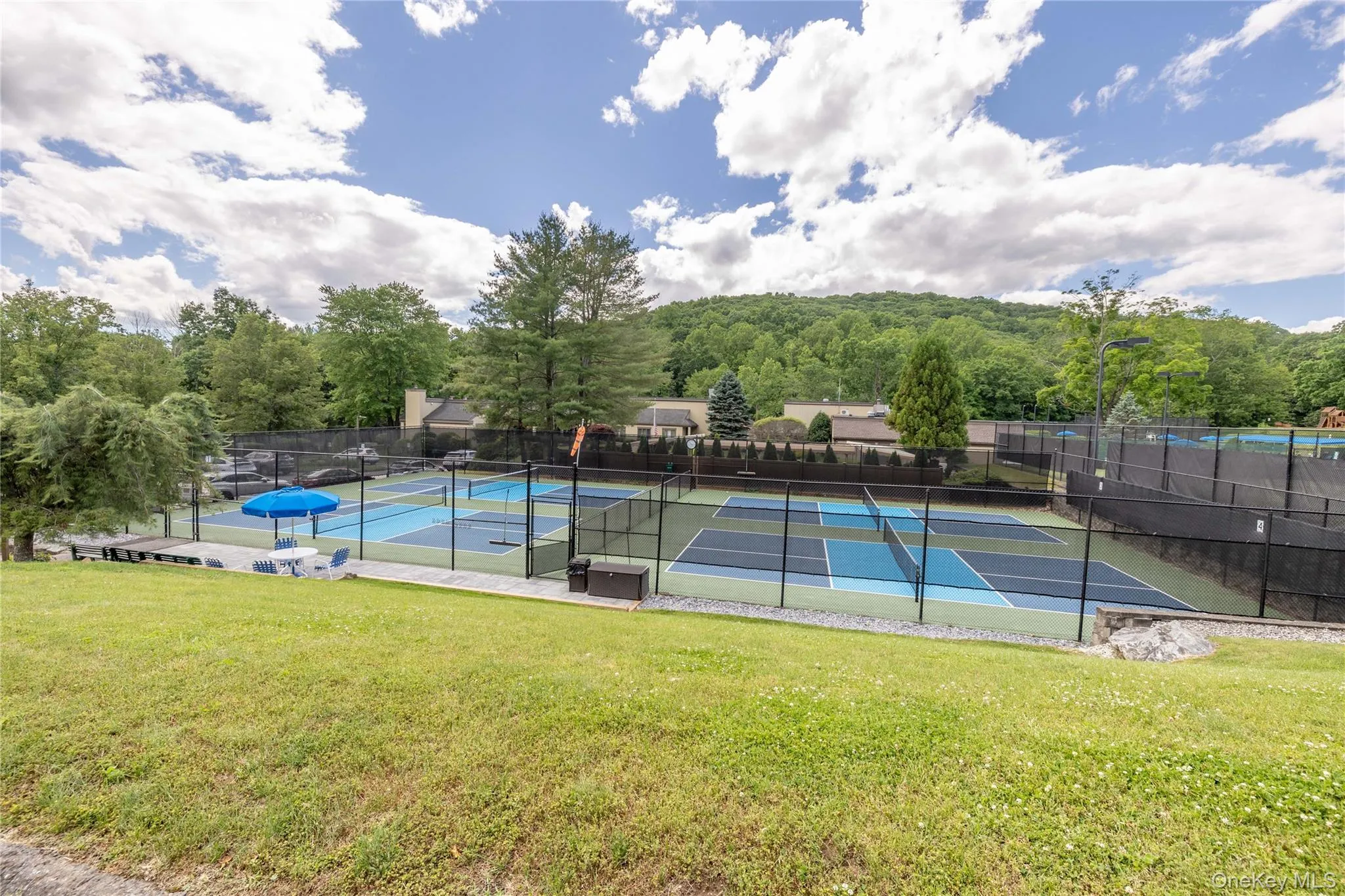 View of tennis court featuring a patio area View of tennis court featuring a patio area