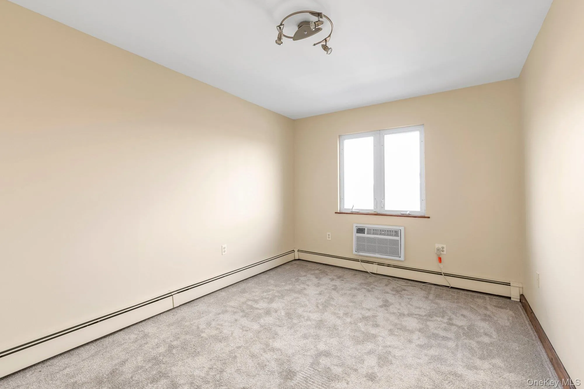 Unfurnished room with carpet flooring, a baseboard heating unit, a baseboard radiator, and a wall unit AC Unfurnished room with carpet flooring, a baseboard heating unit, a baseboard radiator, and a wall unit AC