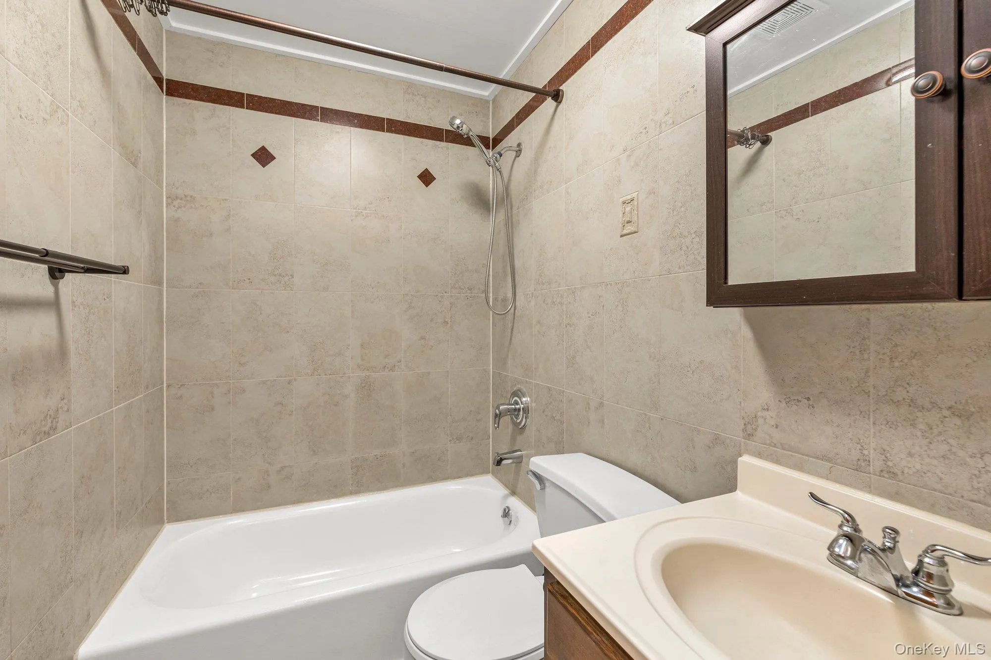 Full bathroom with shower / bathtub combination, vanity, and tile walls Full bathroom with shower / bathtub combination, vanity, and tile walls