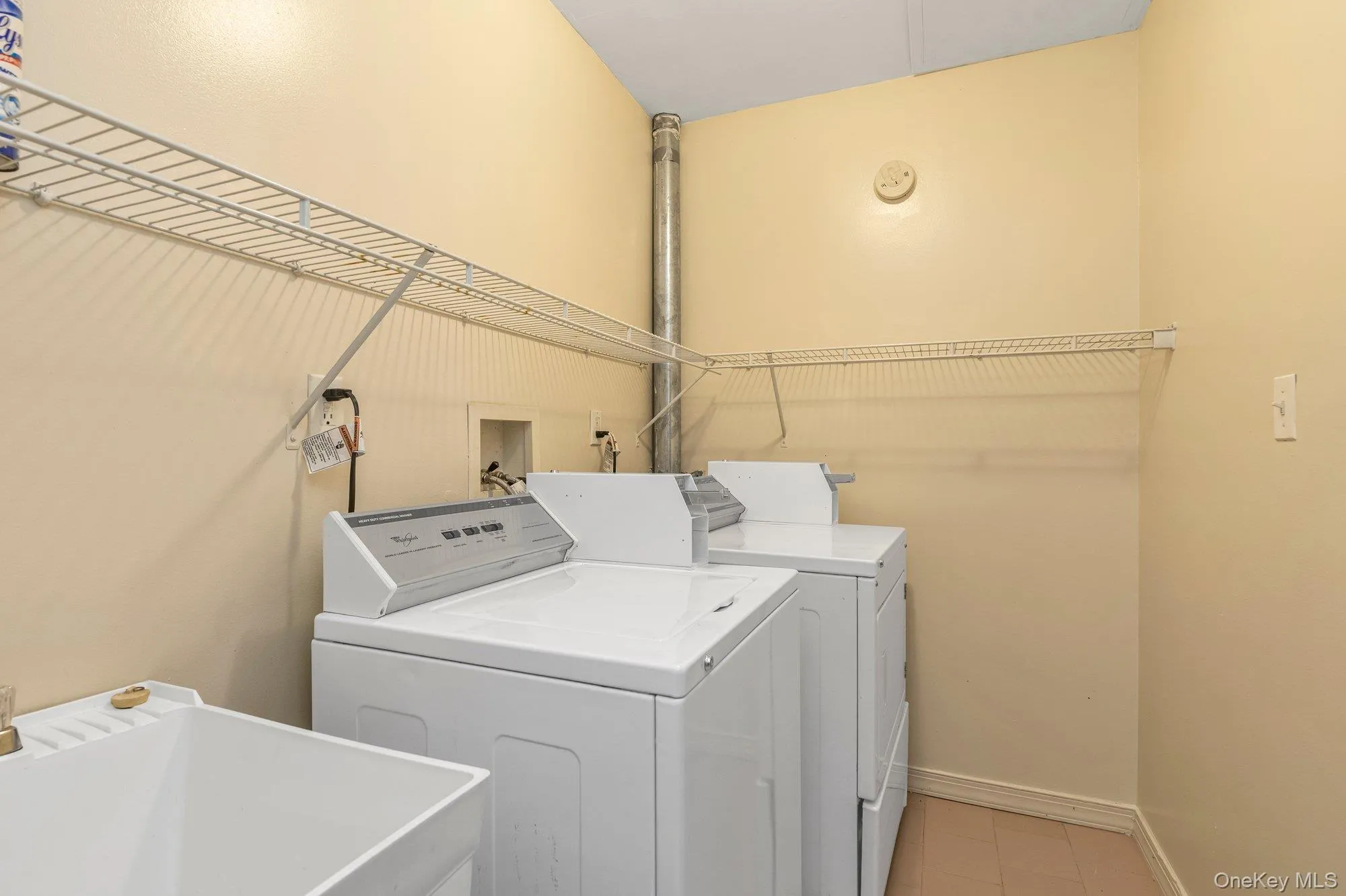 Communal laundry room featuring washer and dryer and light tile patterned floors Communal laundry room featuring washer and dryer and light tile patterned floors
