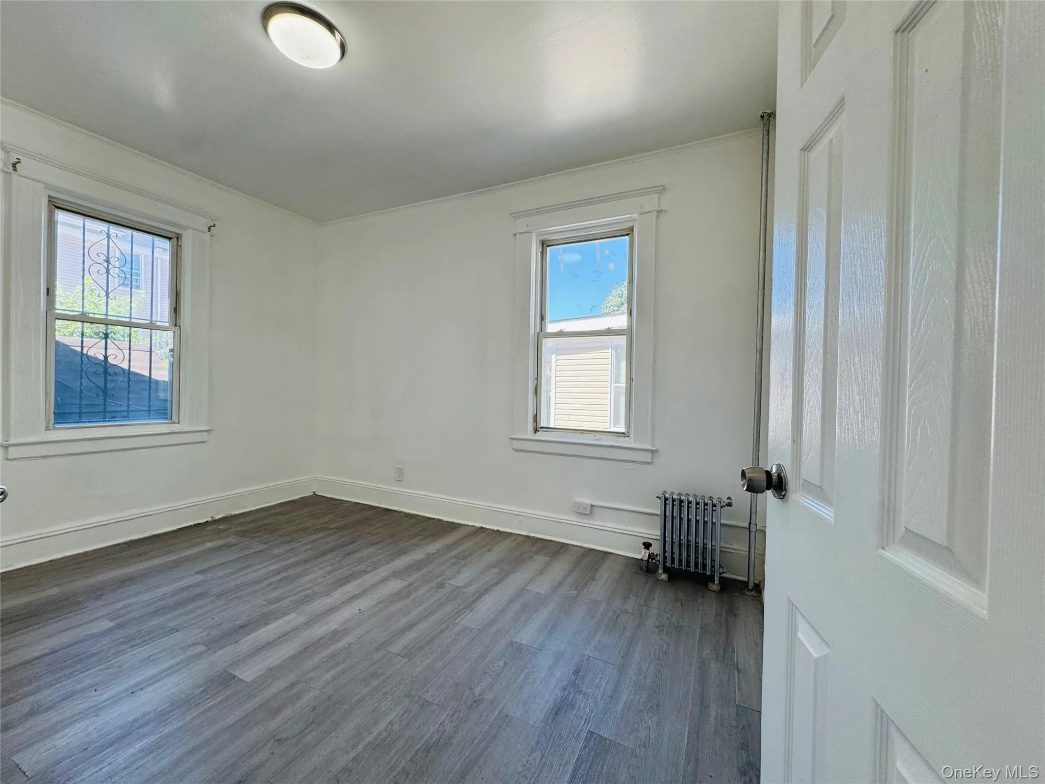 Spare room featuring dark wood finished floors and radiator heating unit Spare room featuring dark wood finished floors and radiator heating unit