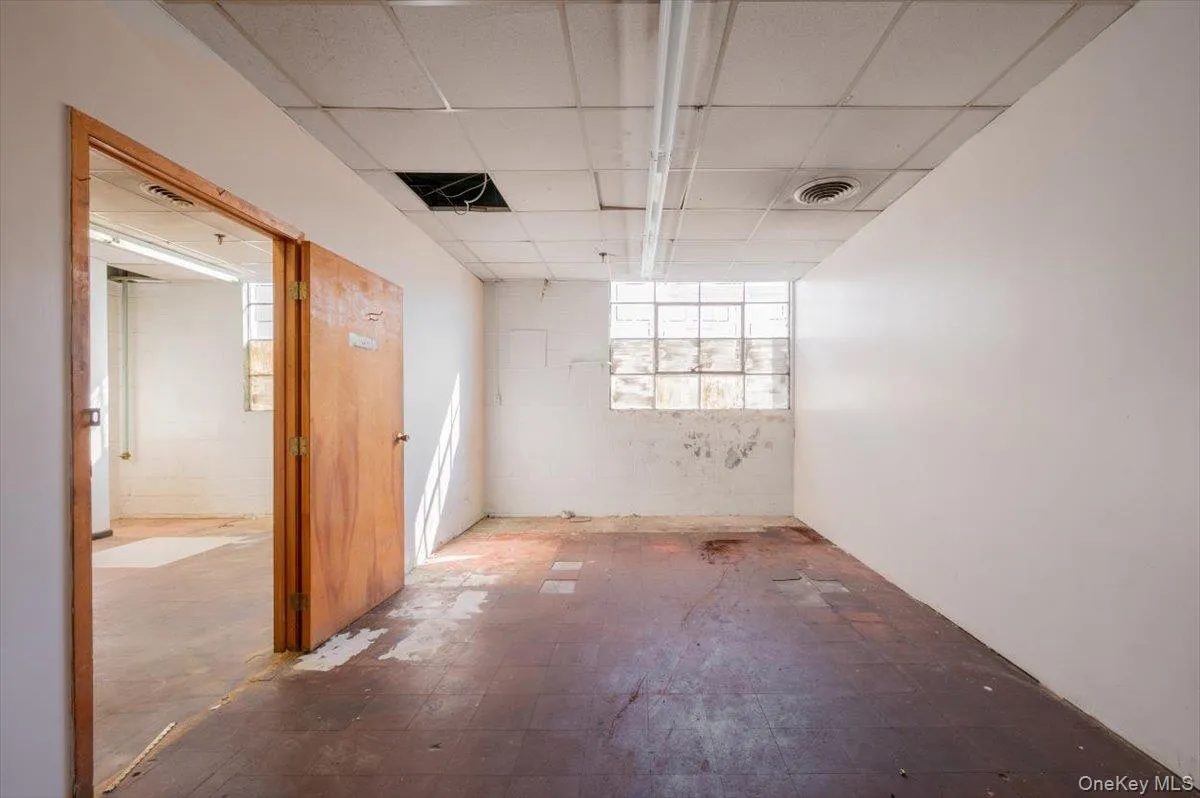 Unfurnished room with a drop ceiling, tile patterned floors, and concrete block wall Unfurnished room with a drop ceiling, tile patterned floors, and concrete block wall