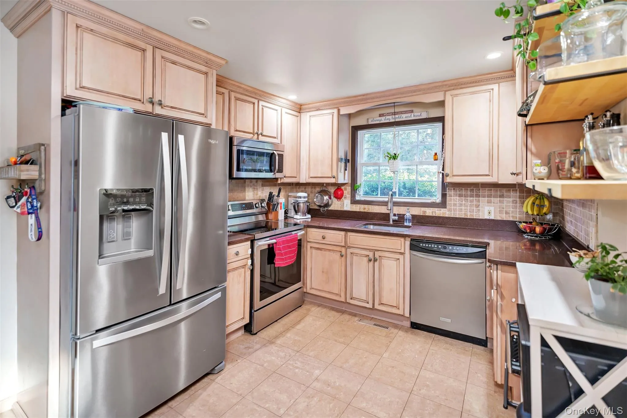 Kitchen with stainless steel appliances, dark countertops, tasteful backsplash, light brown cabinetry, and recessed lighting Kitchen with stainless steel appliances, dark countertops, tasteful backsplash, light brown cabinetry, and recessed lighting