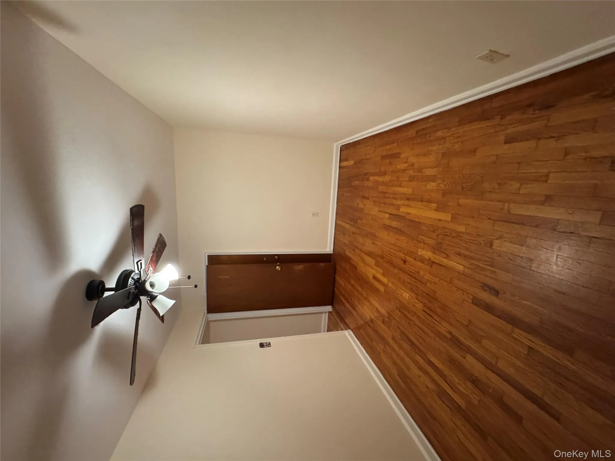 Empty room with dark wood-style flooring and a ceiling fan Empty room with dark wood-style flooring and a ceiling fan