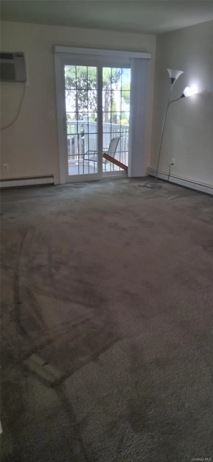Carpeted spare room featuring a baseboard heating unit and an AC wall unit Carpeted spare room featuring a baseboard heating unit and an AC wall unit