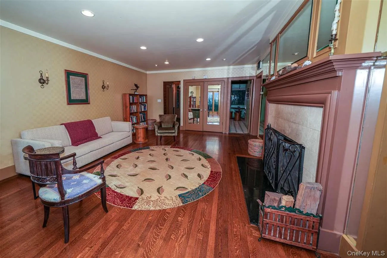 Living area featuring a tiled fireplace, wood finished floors, french doors, wallpapered walls, and ornamental molding Living area featuring a tiled fireplace, wood finished floors, french doors, wallpapered walls, and ornamental molding
