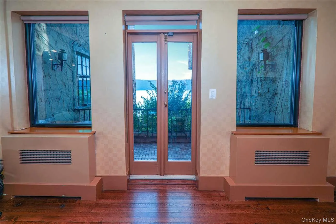 Doorway to outside featuring wood-type flooring and baseboards Doorway to outside featuring wood-type flooring and baseboards