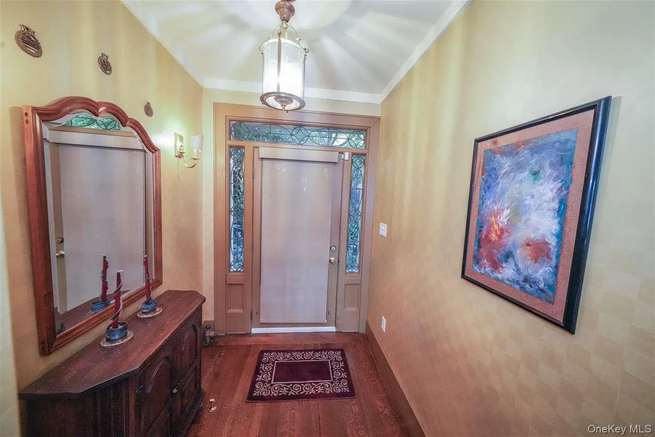Foyer entrance featuring dark wood-type flooring and ornamental molding Foyer entrance featuring dark wood-type flooring and ornamental molding