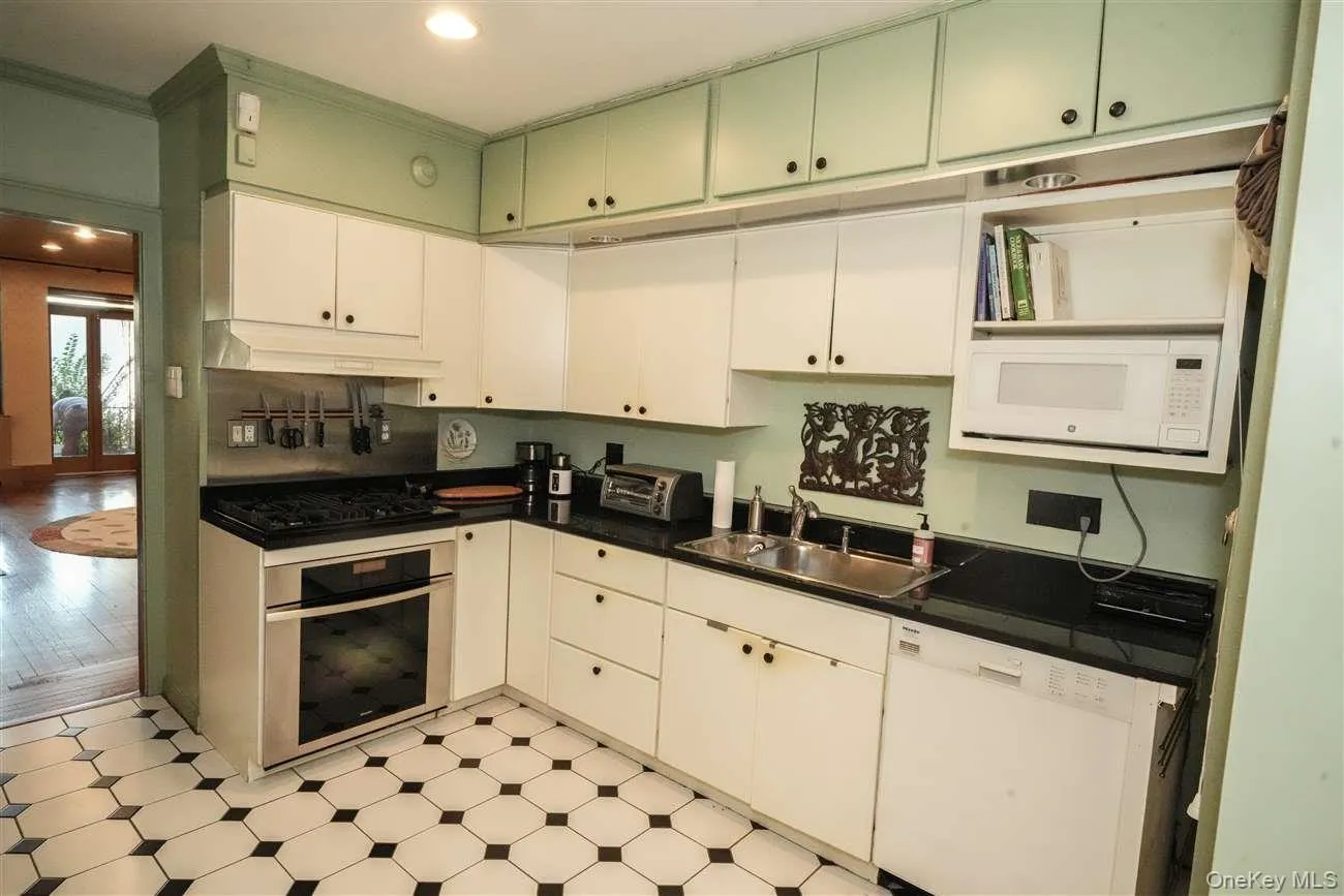 Kitchen featuring white appliances, light flooring, recessed lighting, under cabinet range hood, and crown molding Kitchen featuring white appliances, light flooring, recessed lighting, under cabinet range hood, and crown molding