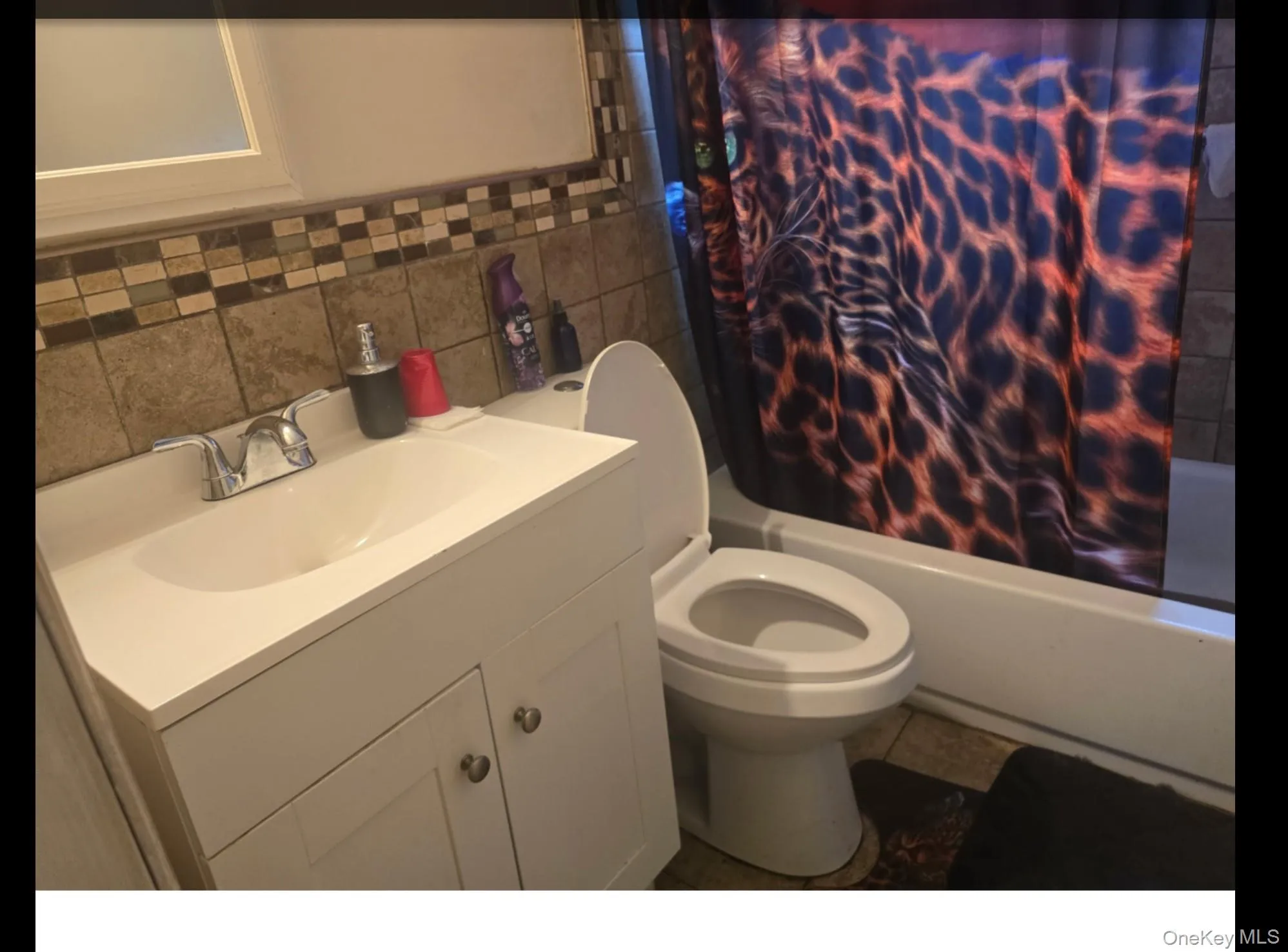 Full bath featuring shower / bathtub combination with curtain, vanity, tile walls, and tile patterned floors Full bath featuring shower / bathtub combination with curtain, vanity, tile walls, and tile patterned floors