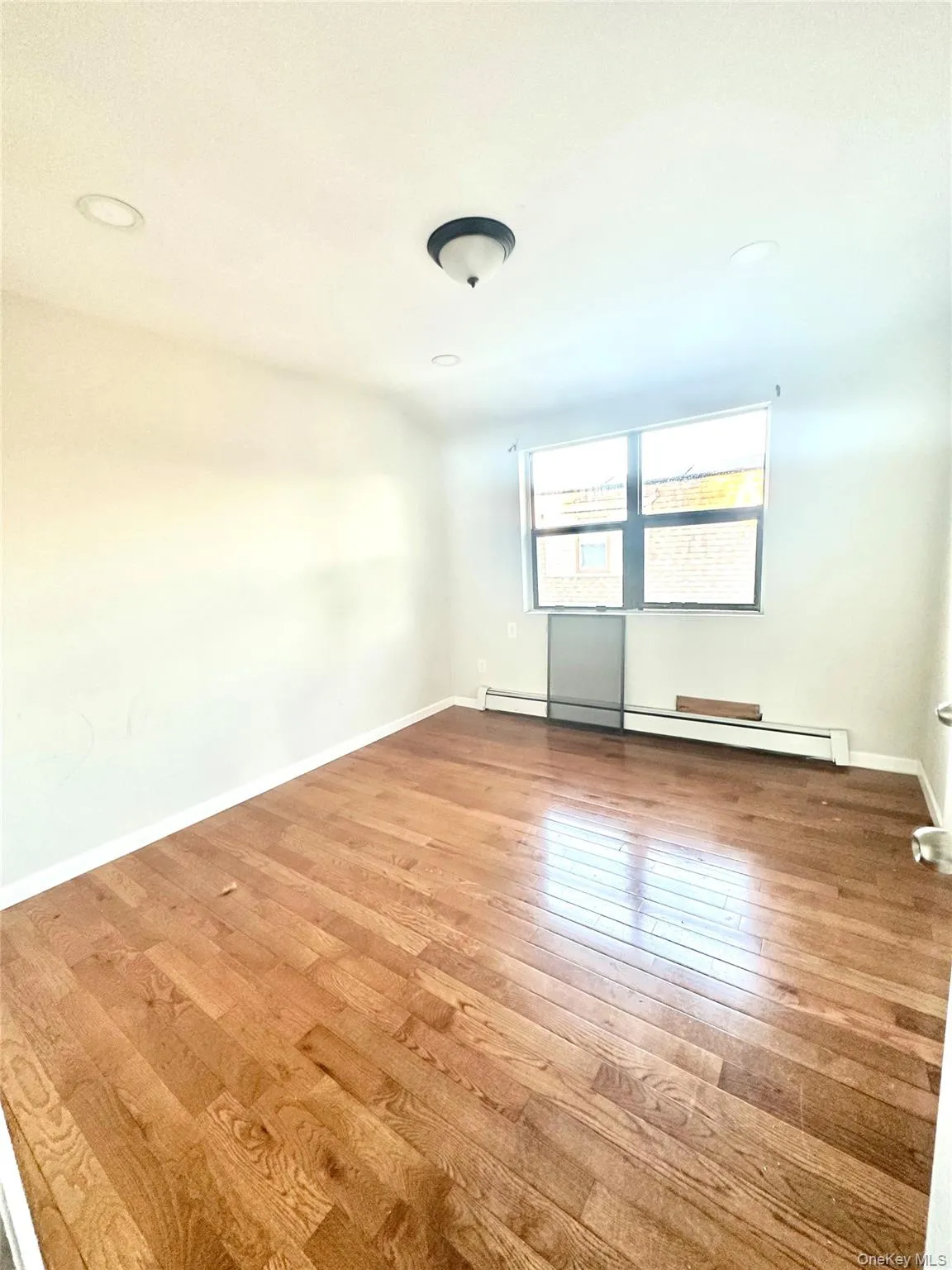 Unfurnished room with baseboard heating and hardwood / wood-style flooring Unfurnished room with baseboard heating and hardwood / wood-style flooring