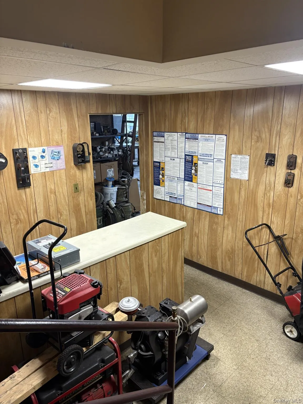 Workout room with a paneled ceiling, wood walls, and light flooring Workout room with a paneled ceiling, wood walls, and light flooring