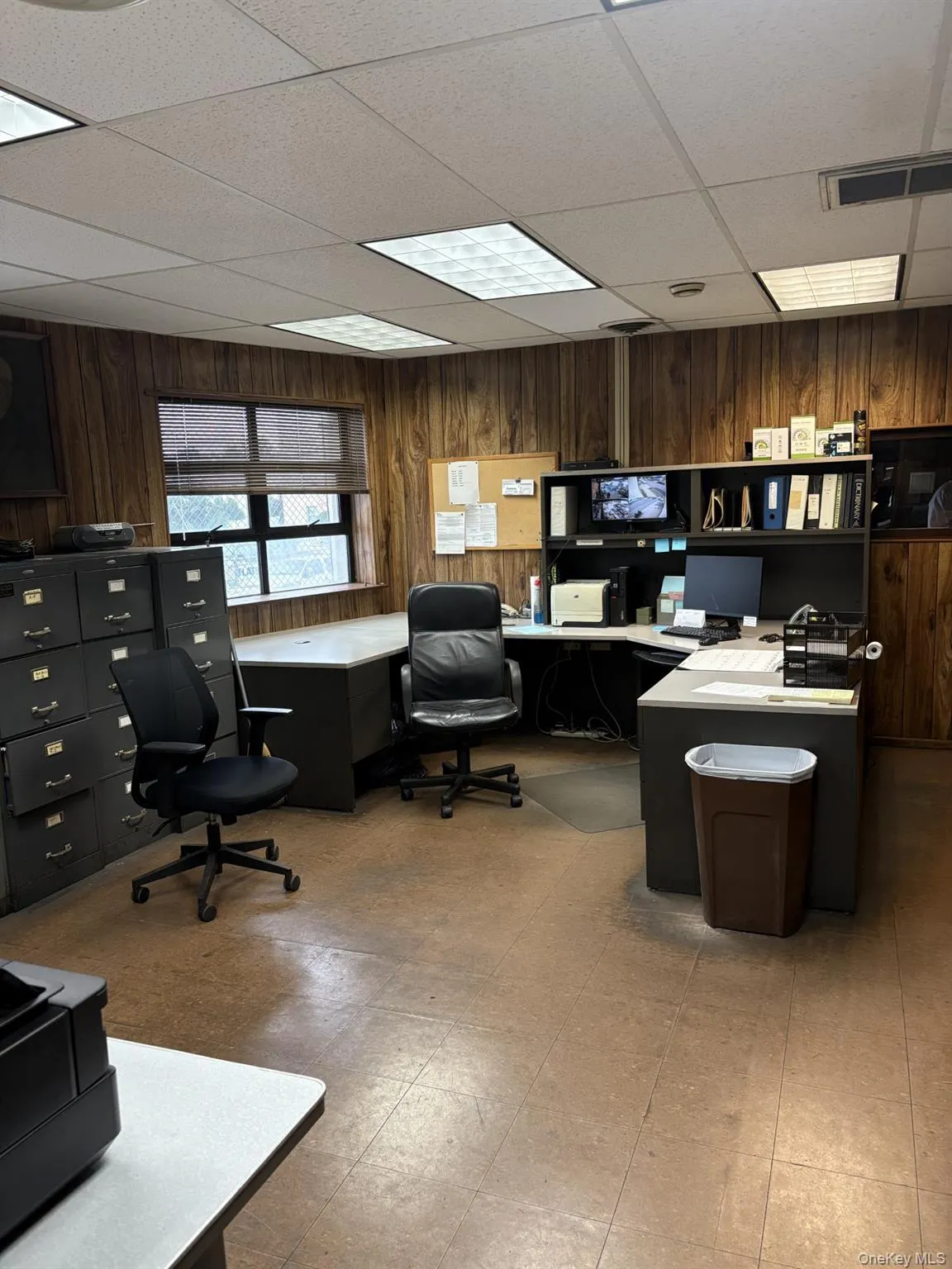 Home office featuring wooden walls, a paneled ceiling, and light flooring Home office featuring wooden walls, a paneled ceiling, and light flooring