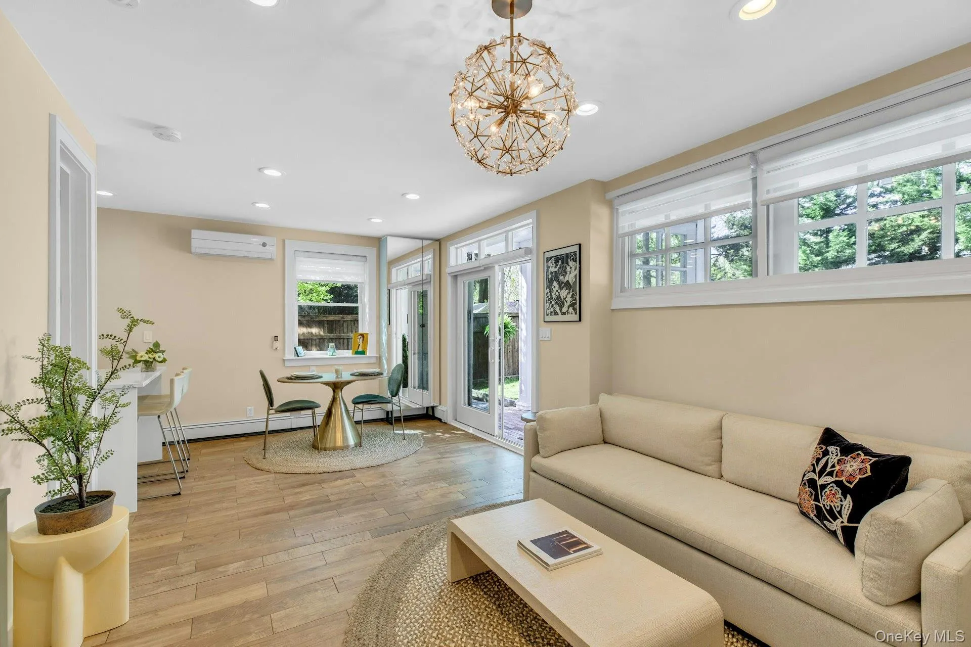 Living room with plenty of natural light, light wood-style floors, recessed lighting, and a chandelier Living room with plenty of natural light, light wood-style floors, recessed lighting, and a chandelier