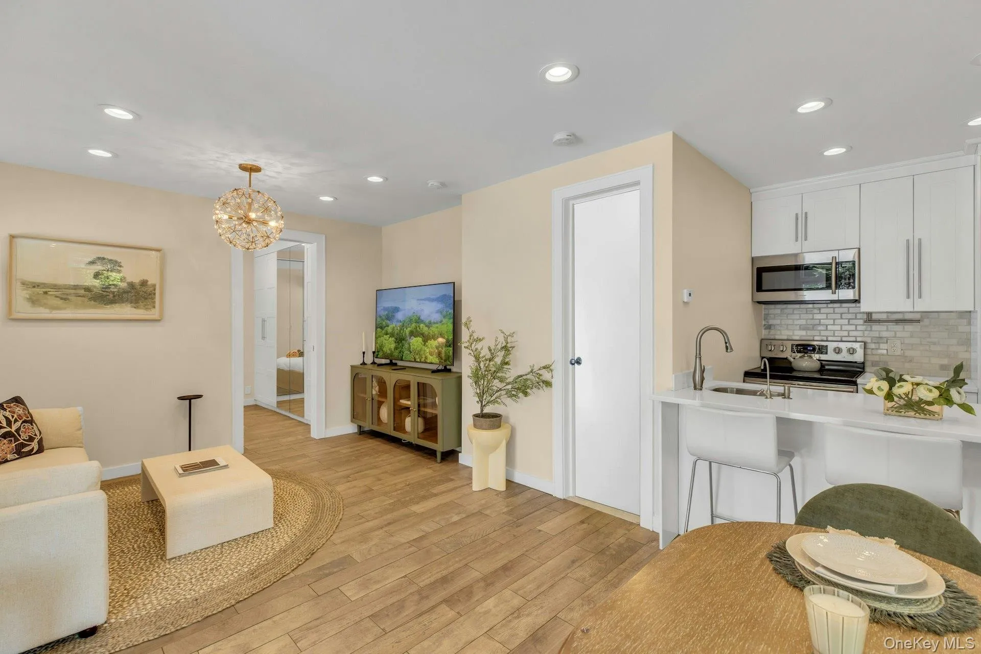 Living room with light wood-type flooring, recessed lighting, baseboards, and a chandelier Living room with light wood-type flooring, recessed lighting, baseboards, and a chandelier