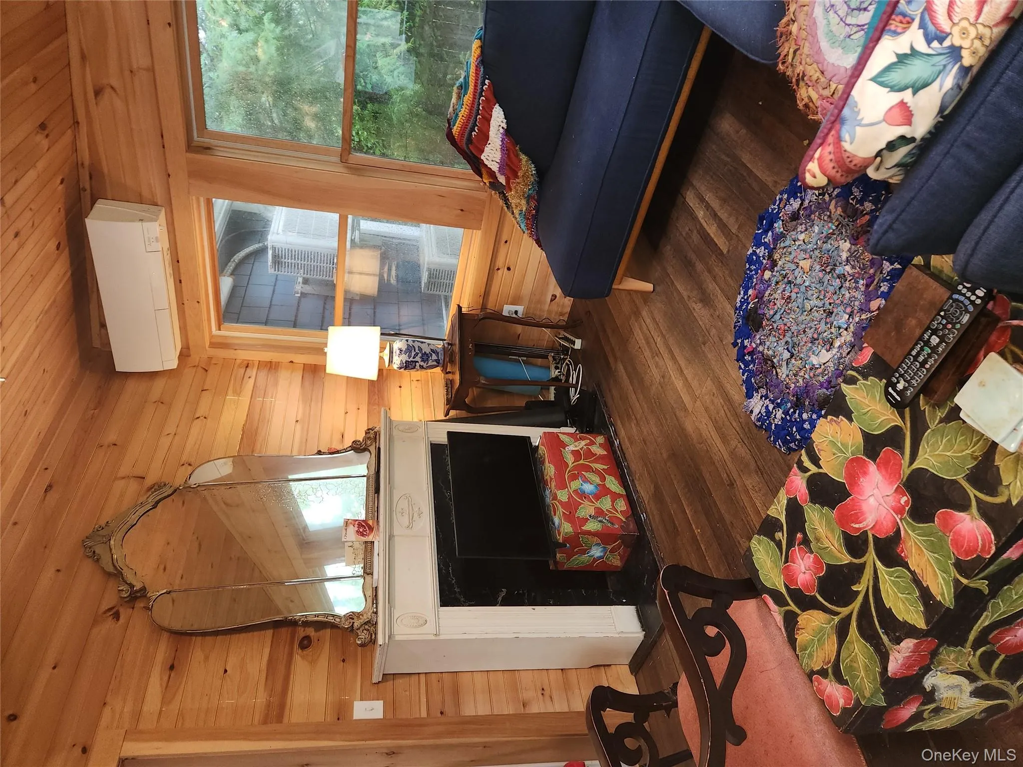 Living area featuring wood finished floors, wooden ceiling, an AC wall unit, wood walls, and plenty of natural light Living area featuring wood finished floors, wooden ceiling, an AC wall unit, wood walls, and plenty of natural light