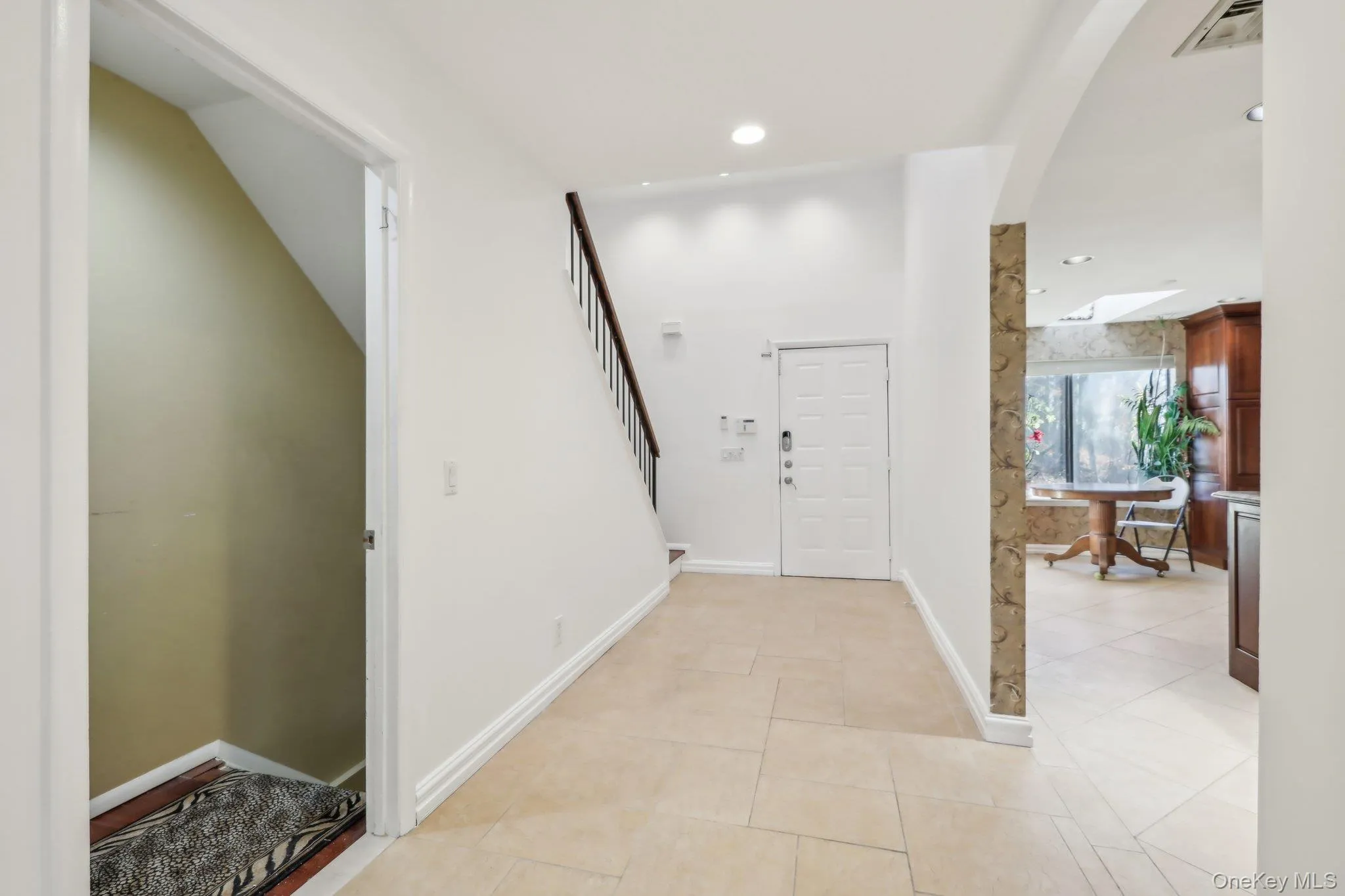 Corridor with arched walkways, light tile patterned floors, recessed lighting, and stairway Corridor with arched walkways, light tile patterned floors, recessed lighting, and stairway
