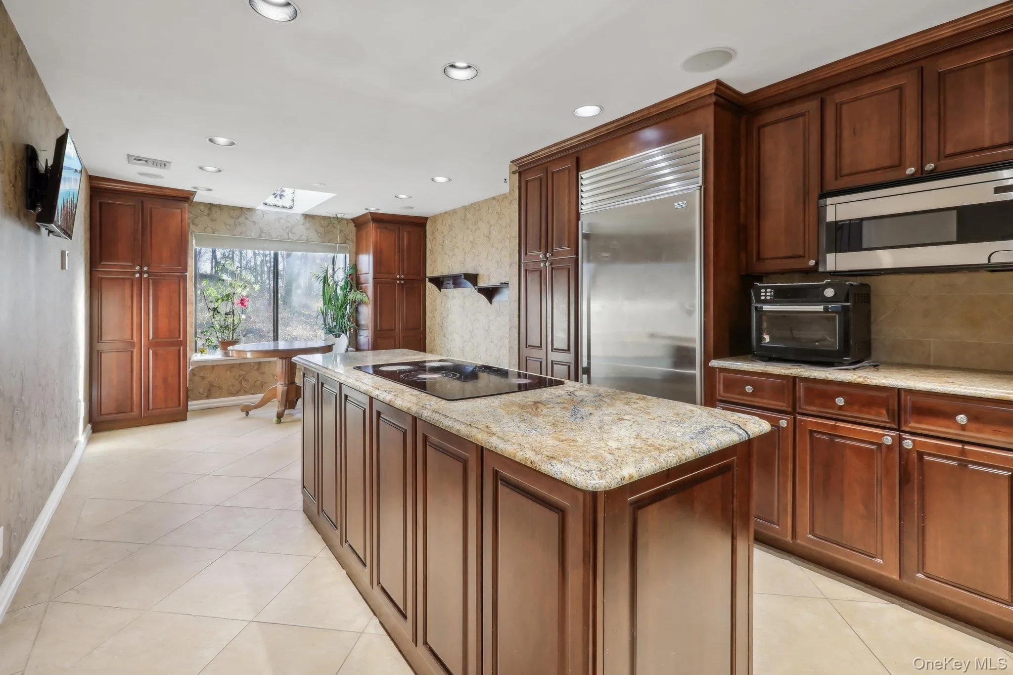 Kitchen with wallpapered walls, appliances with stainless steel finishes, recessed lighting, light tile patterned floors, and light stone countertops Kitchen with wallpapered walls, appliances with stainless steel finishes, recessed lighting, light tile patterned floors, and light stone countertops