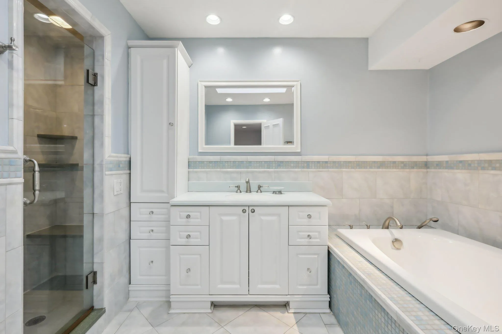 Full bathroom featuring vanity, a stall shower, a garden tub, tile walls, and light tile patterned floors Full bathroom featuring vanity, a stall shower, a garden tub, tile walls, and light tile patterned floors