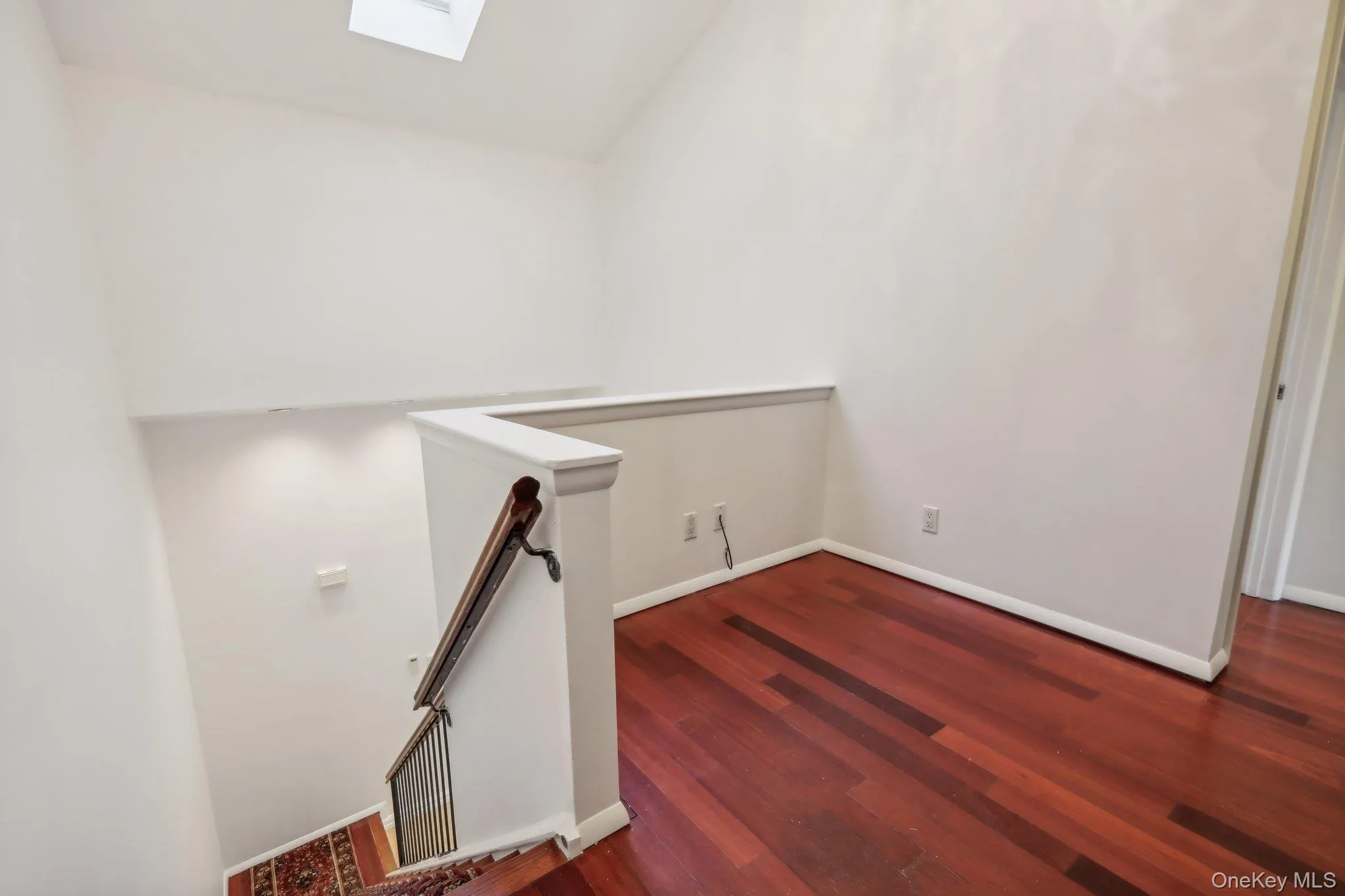 Stairway with a skylight, wood finished floors, and vaulted ceiling Stairway with a skylight, wood finished floors, and vaulted ceiling