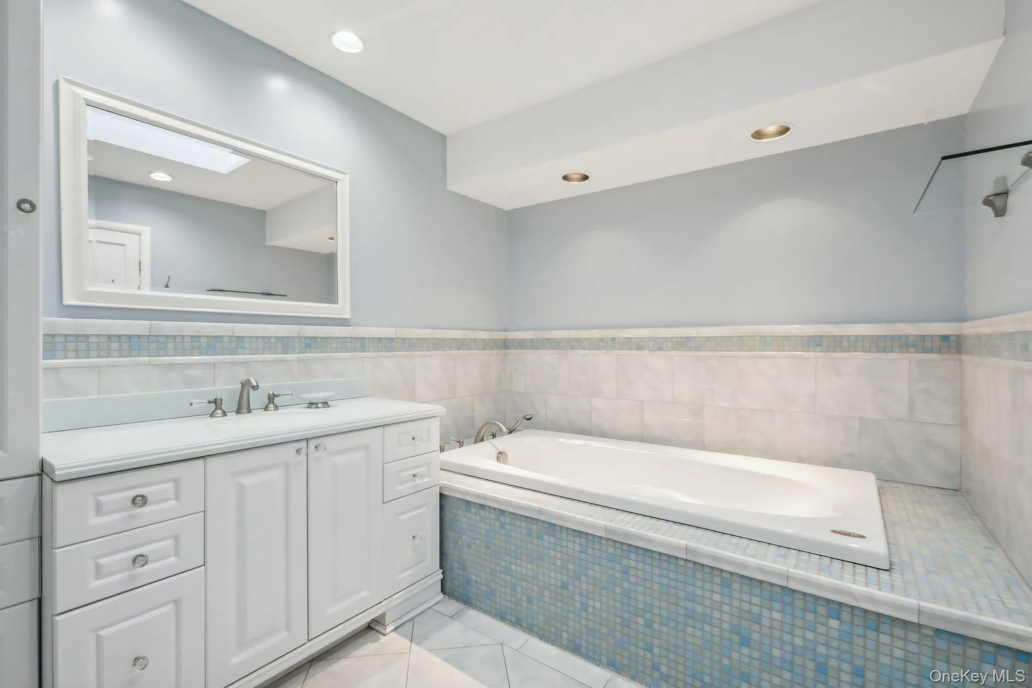 Bathroom featuring a bath, vanity, light tile patterned flooring, recessed lighting, and a wainscoted wall Bathroom featuring a bath, vanity, light tile patterned flooring, recessed lighting, and a wainscoted wall