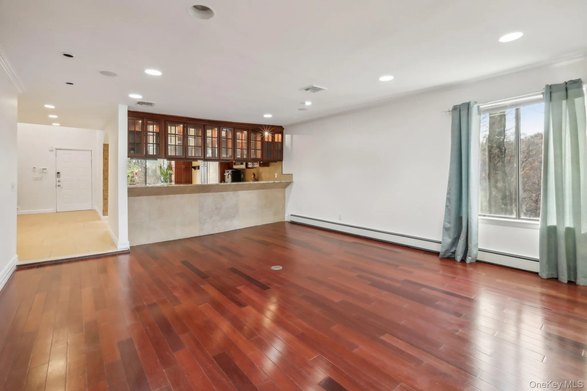 Unfurnished living room with dark wood-style floors, recessed lighting, and a baseboard heating unit Unfurnished living room with dark wood-style floors, recessed lighting, and a baseboard heating unit